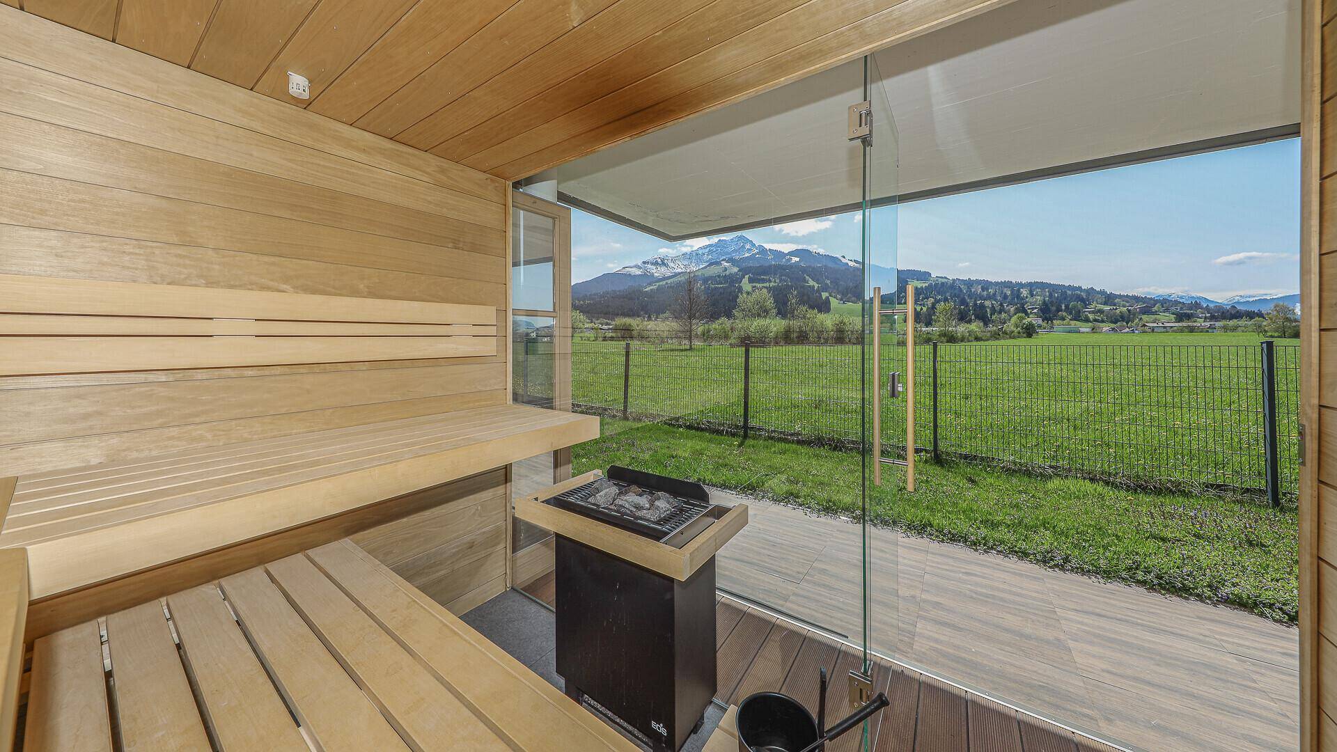 Moderne Sauna mit Holzausstattung und Panoramafenster, das einen direkten Blick auf die Berge bietet.