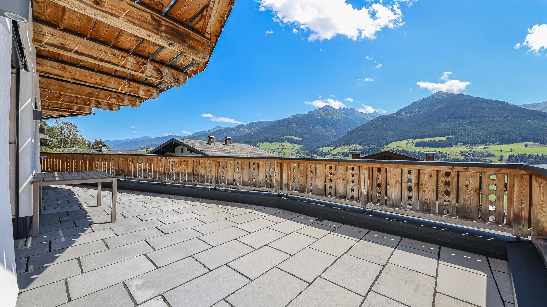 Große Sonnenterrasse mit Steinplatten und atemberaubendem Bergblick.