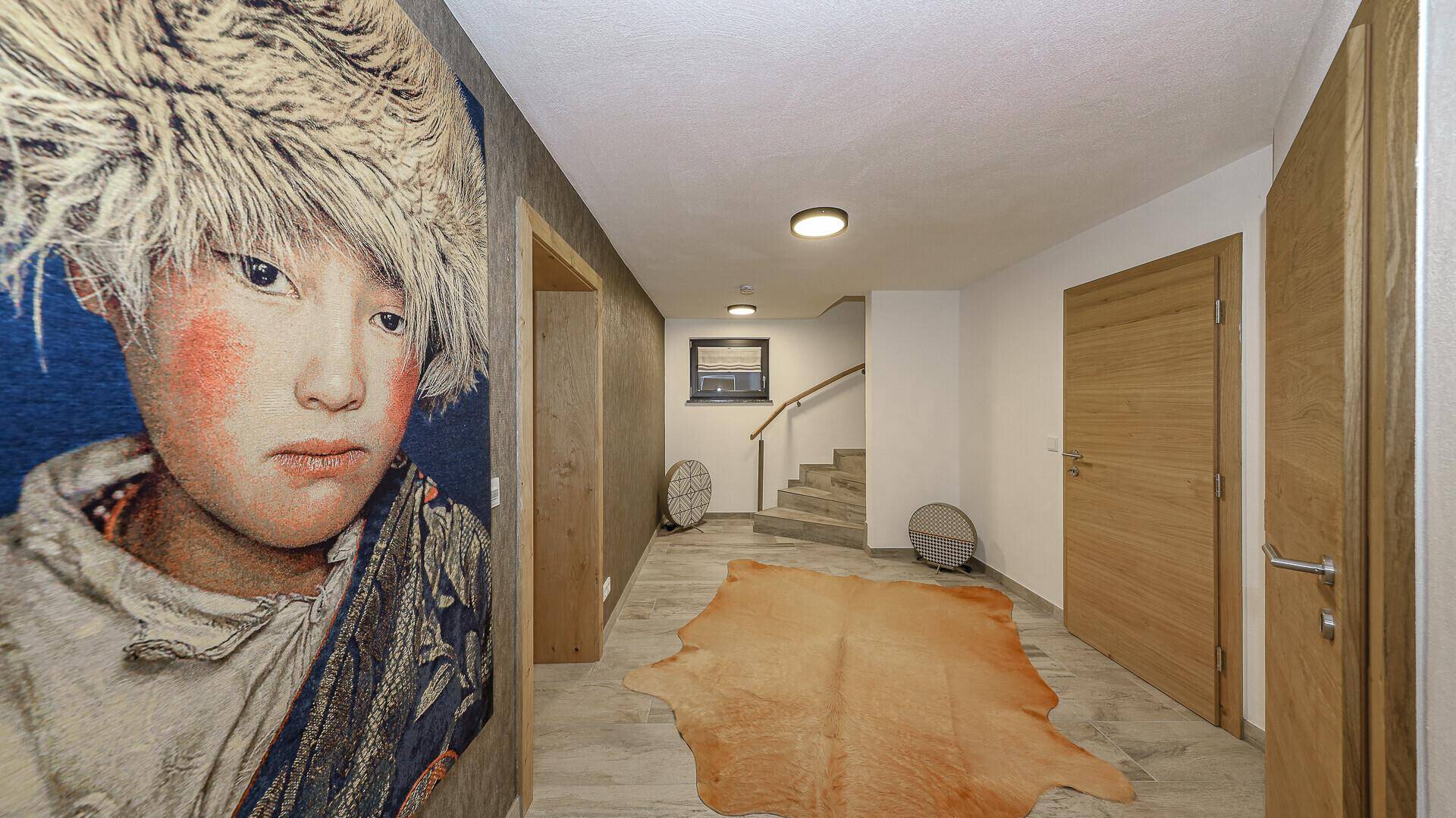 Geräumiger Flur mit Kunstwerk, Treppe und hellem Bodenbelag.
