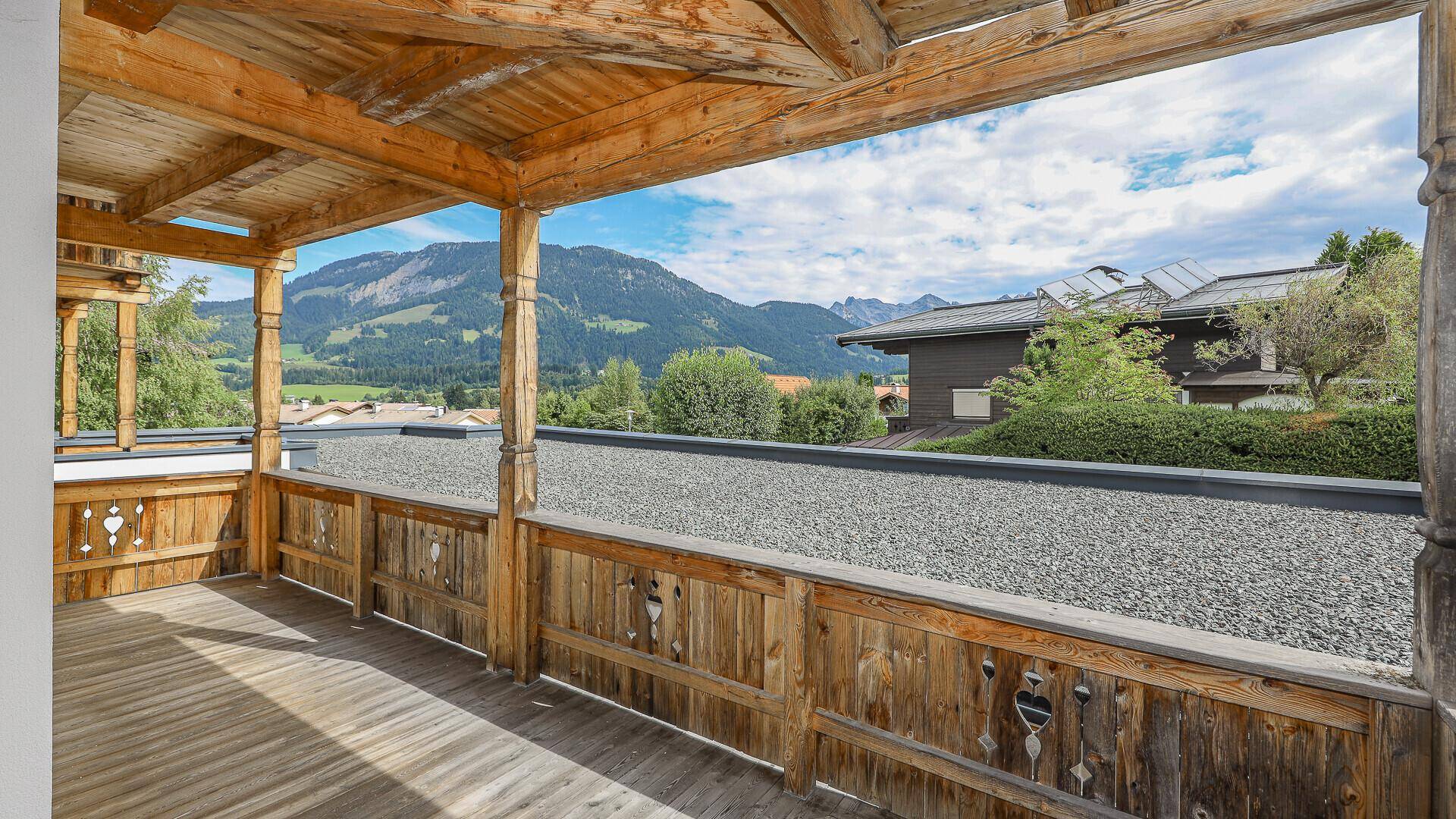 Geräumiger Holzbalkon mit Bergblick und traditionellen Schnitzereien.