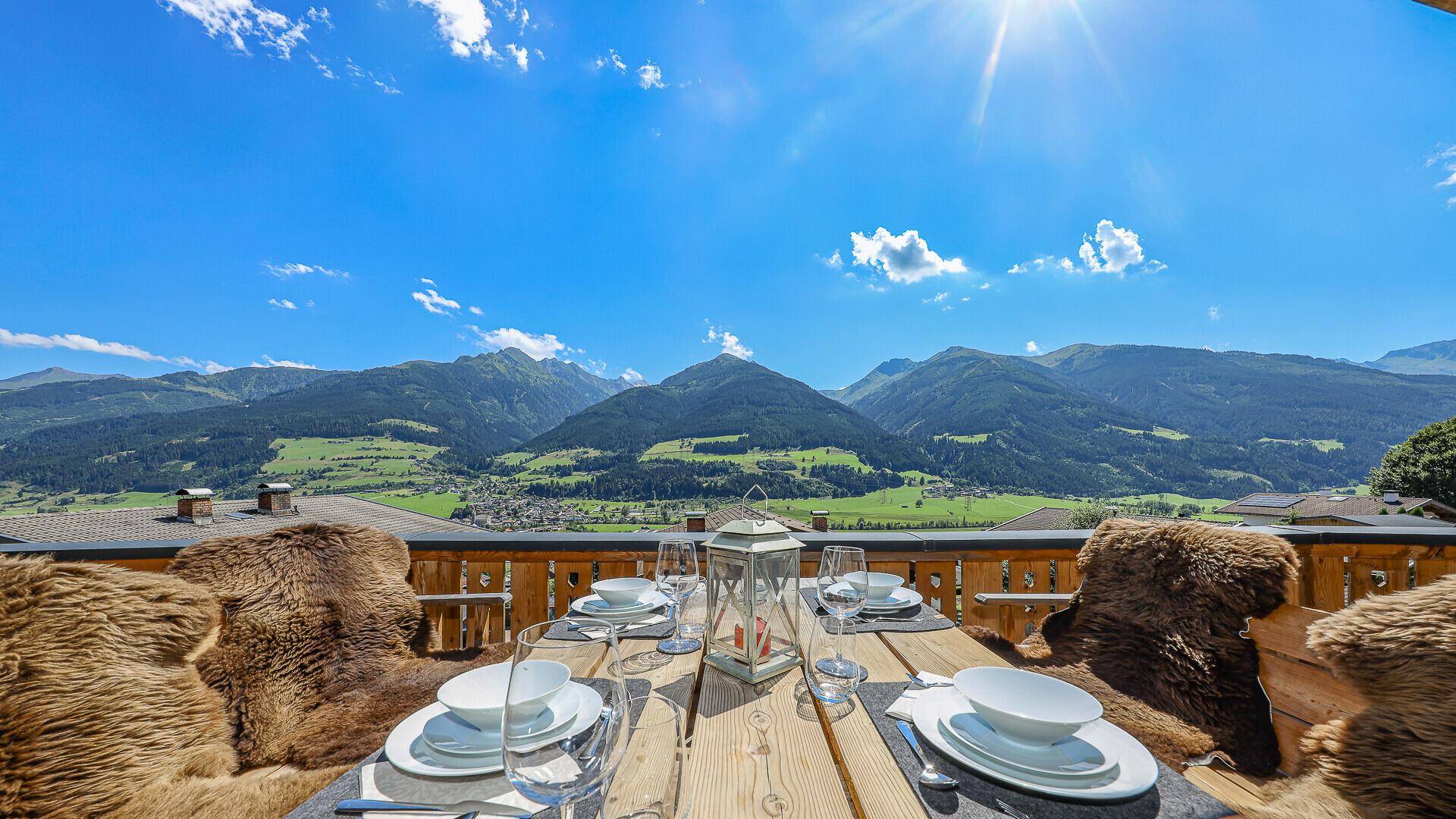 Gedeckter Esstisch auf der Terrasse mit Panoramablick auf die umliegenden Berge.