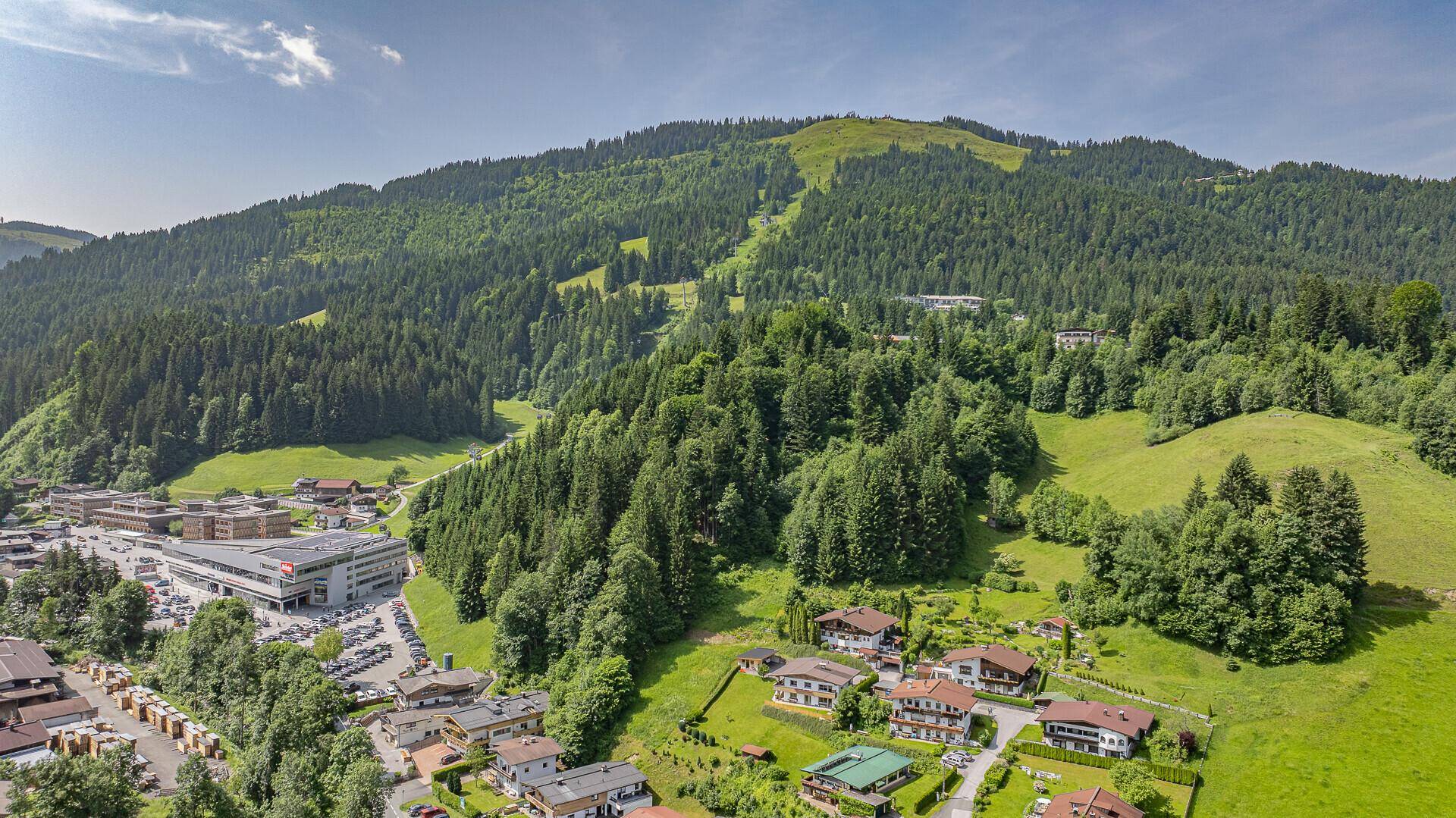 Weitläufige Ansicht einer Siedlung am Fuße eines bewaldeten Berges mit Skipiste.