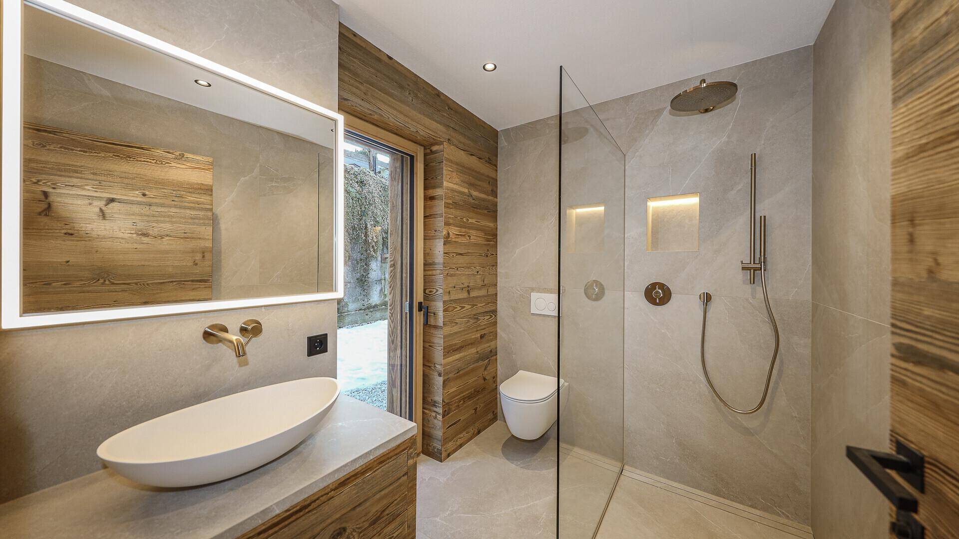 Modernes Badezimmer mit begehbarer Dusche, ovalem Waschbecken und Fenster.
