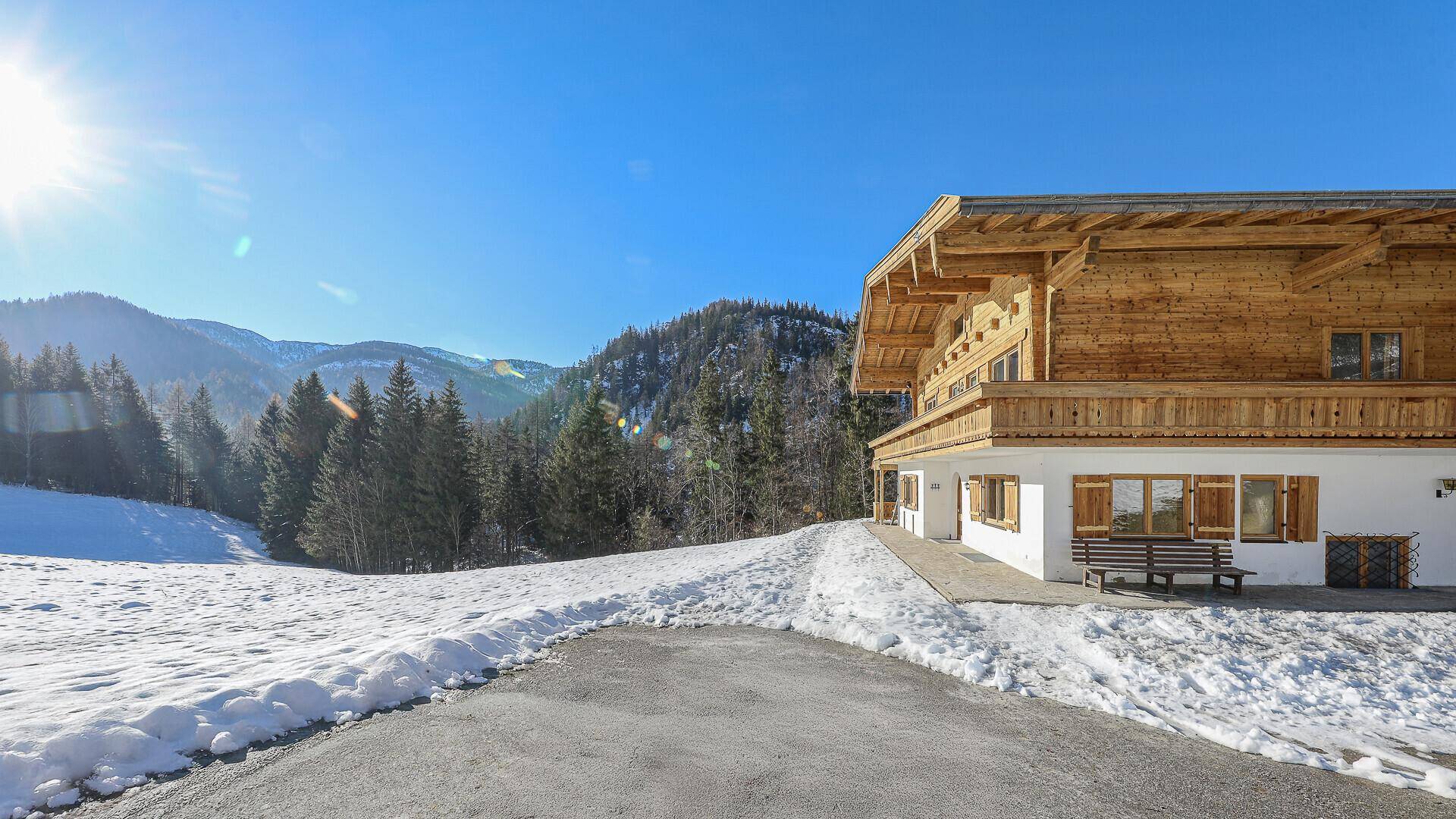 Sonnige Ansicht des Chalets in winterlicher Umgebung mit verschneiten Hügeln und Wäldern.