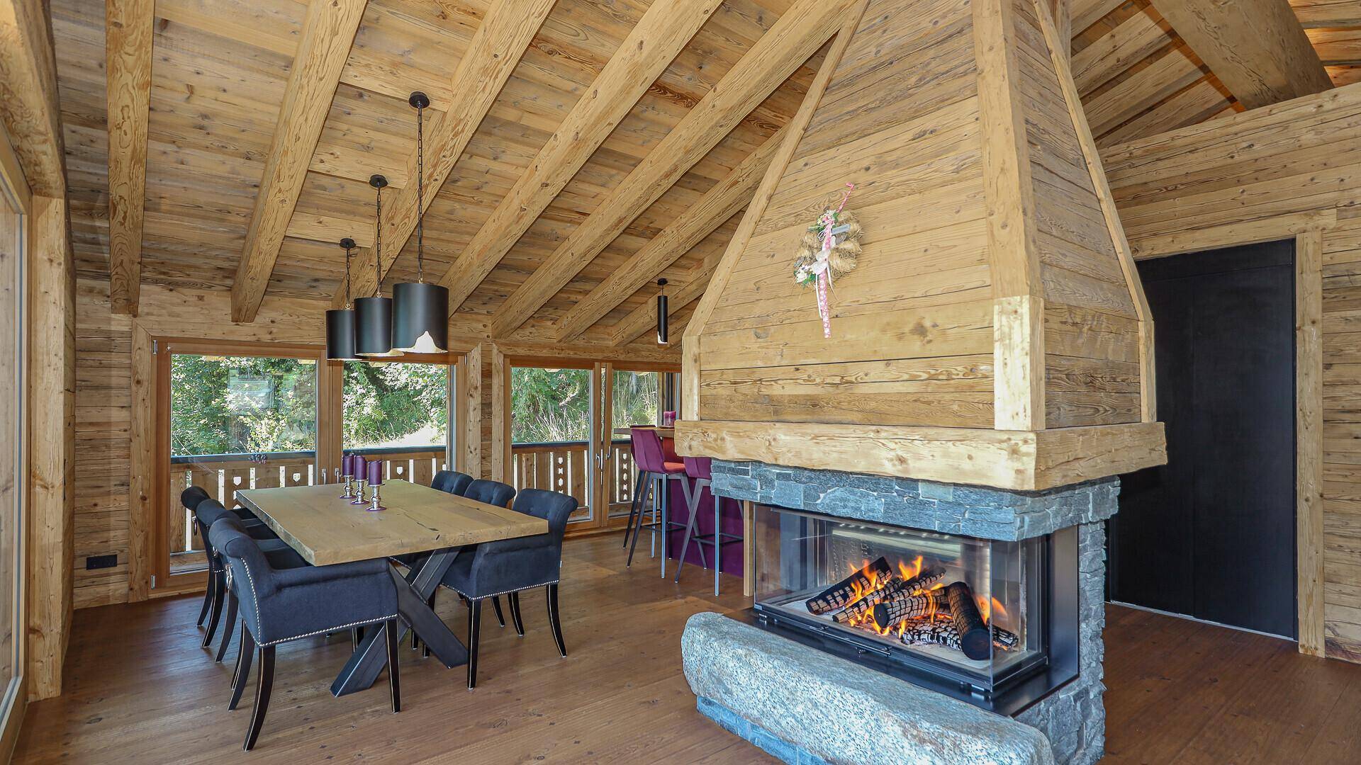 Eleganter Essbereich mit Holztisch, modernen Stühlen und Kamin im Chalet-Stil.