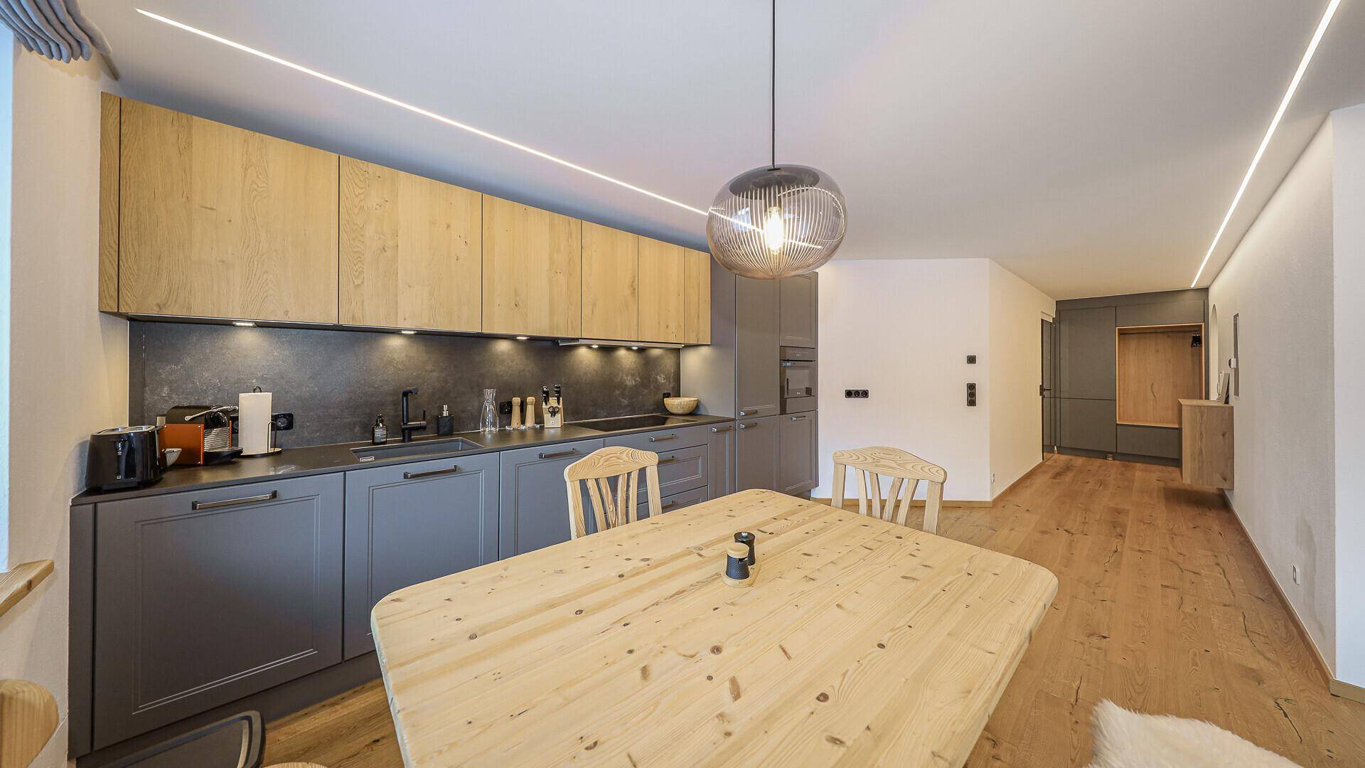 Offene Küche mit modernem Design, Holztisch und integriertem Essbereich.