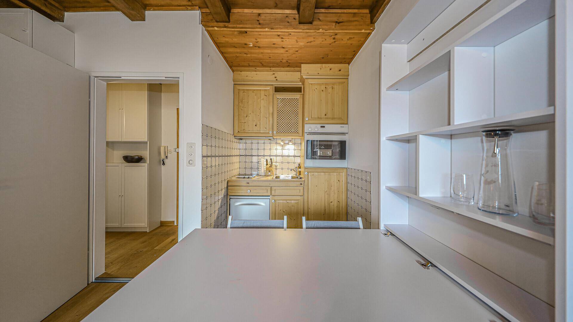 Funktionale Küchenzeile mit Holzelementen, Fliesenrückwand und kleinem Essbereich.
