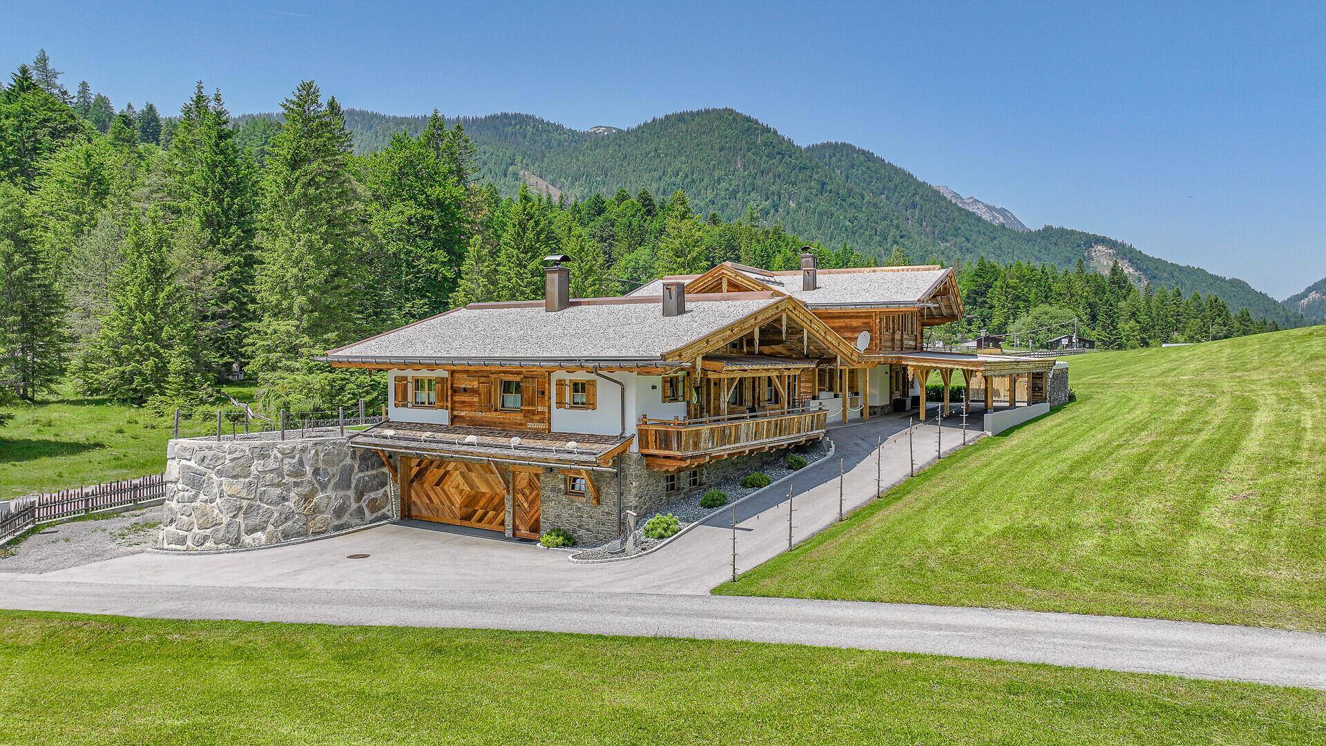 Beeindruckendes Chalet-Anwesen mit traditioneller Holzarchitektur, Garage und weitläufiger Grünfläche.