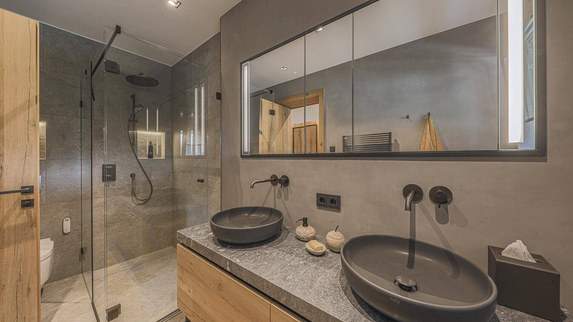 Elegantes Badezimmer mit zwei Waschbecken, großer begehbarer Dusche und modernen Armaturen.