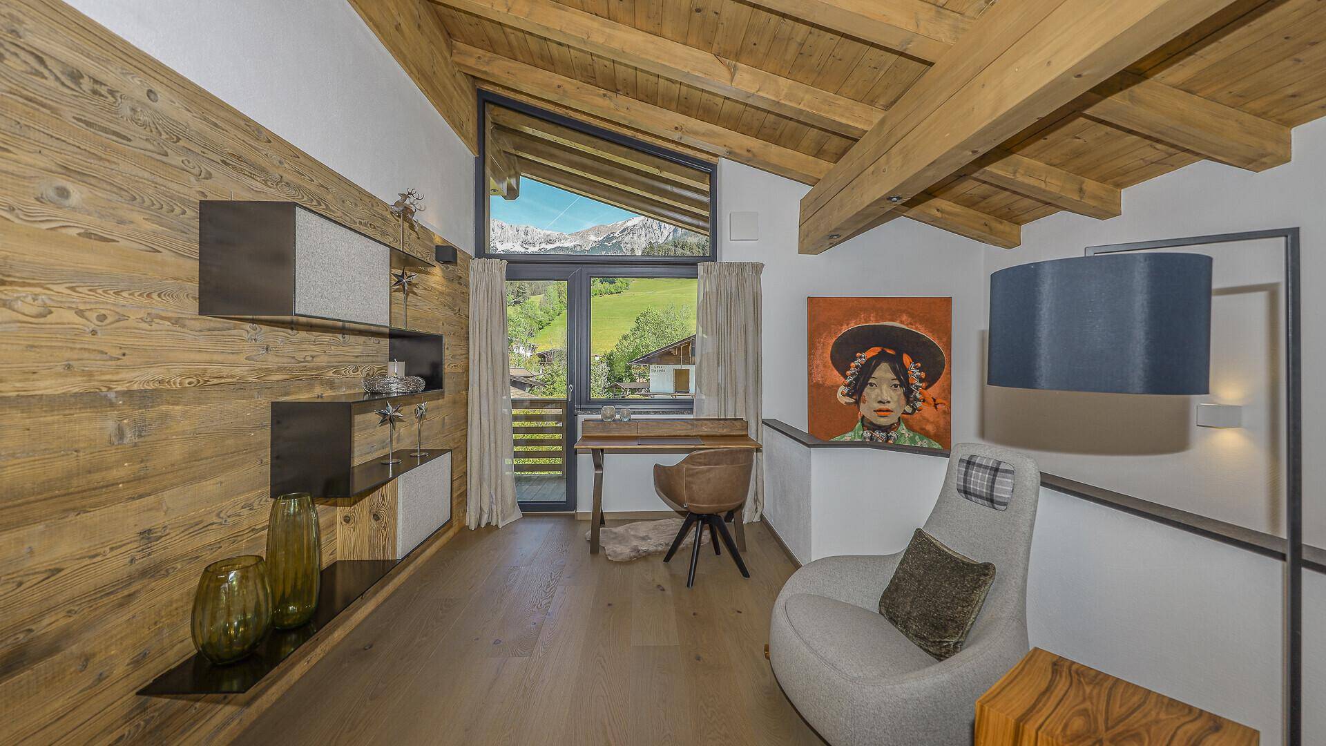 Gemütlicher Arbeitsbereich mit Holzwand, Schreibtisch und Fenster mit Bergblick.