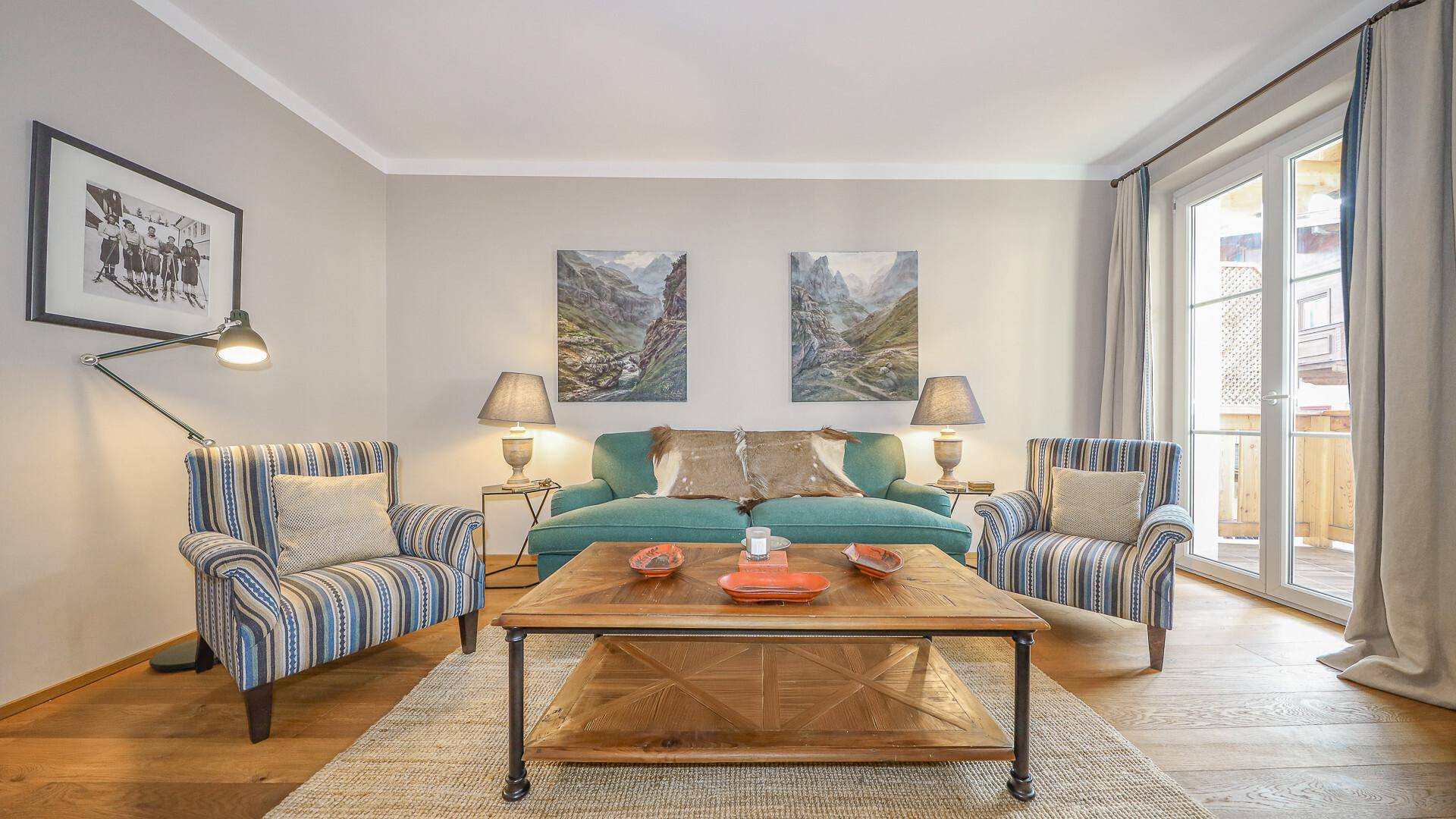 Gemütliches Wohnzimmer mit bequemen Sofas, Holztisch und Zugang zu einem Balkon.