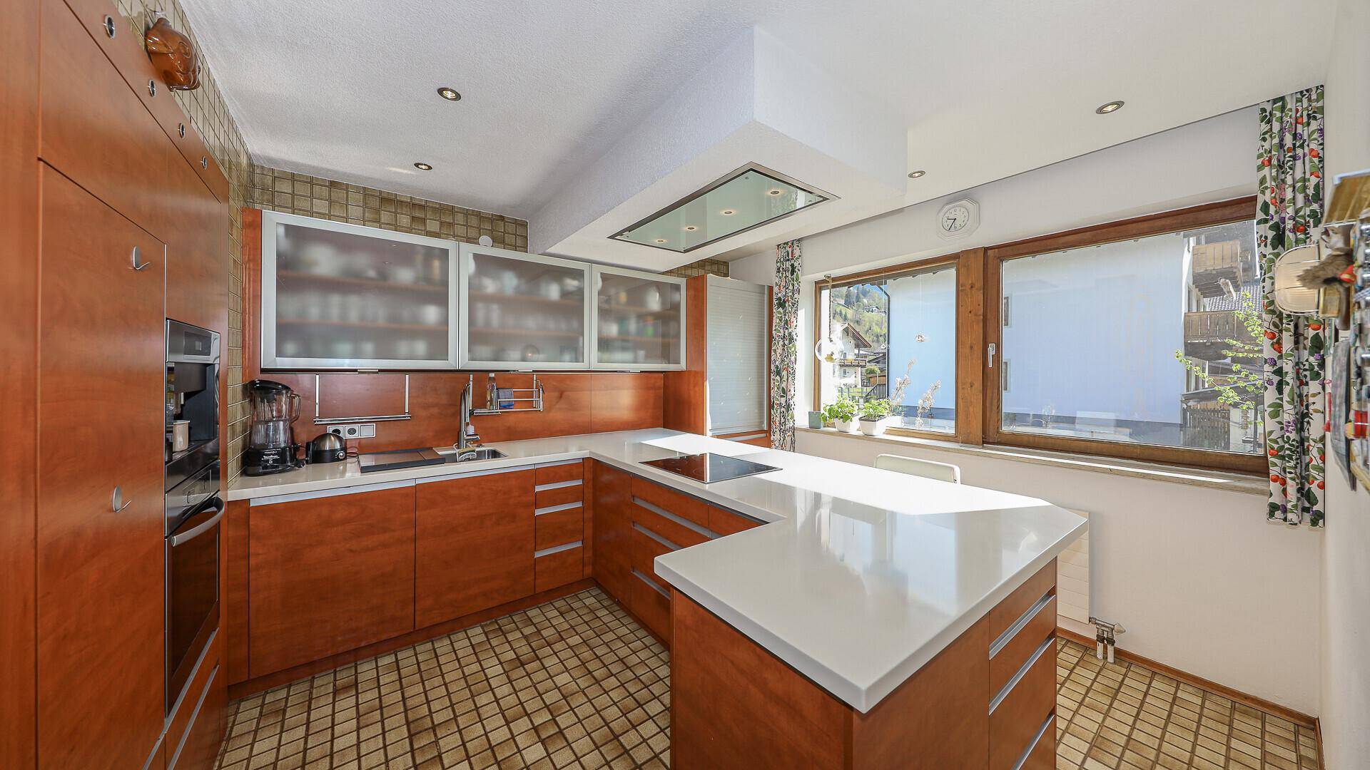 Funktionale Küche mit Holzschränken, hellen Arbeitsplatten und Fensterblick.