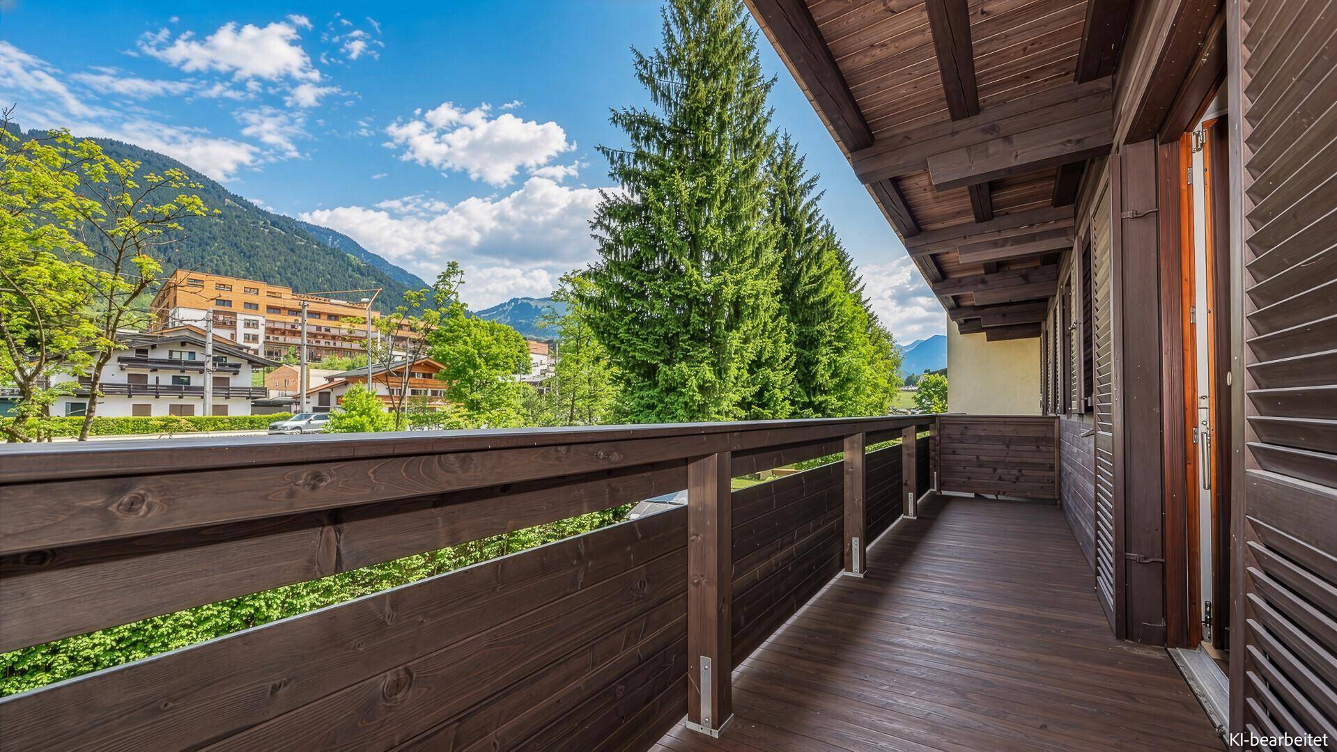 Geräumiger Balkon mit Holzgeländer und weitem Blick auf die Berge und Umgebung.