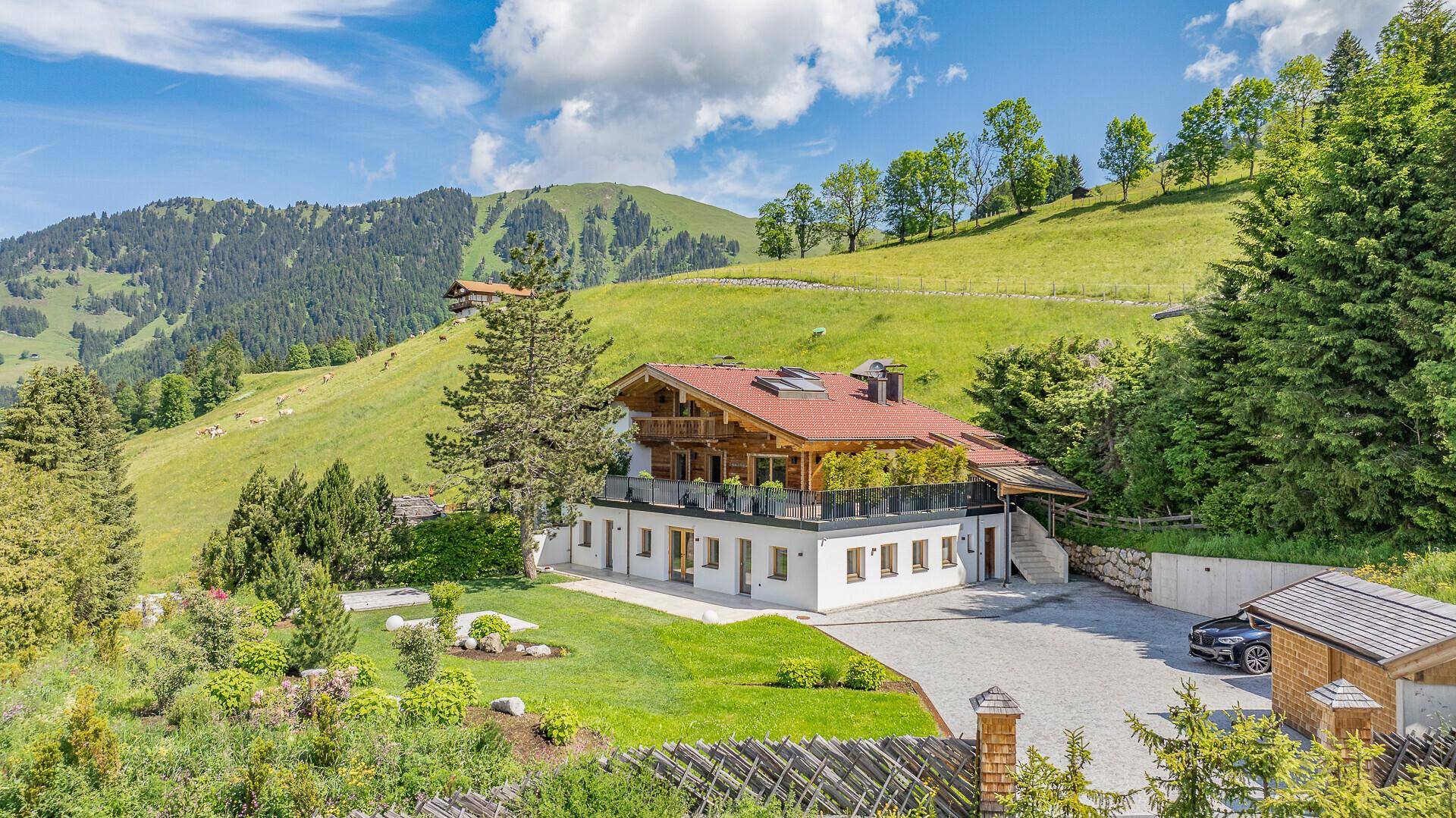Modernes Chalet in den Alpen mit weitläufigem Garten und Panoramablick auf die Berge.