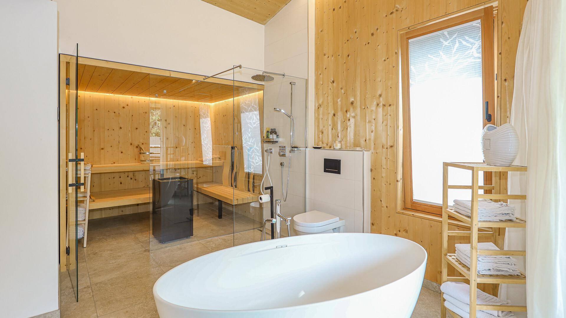 Modernes Badezimmer mit freistehender Badewanne, begehbarer Dusche, Sauna und WC.