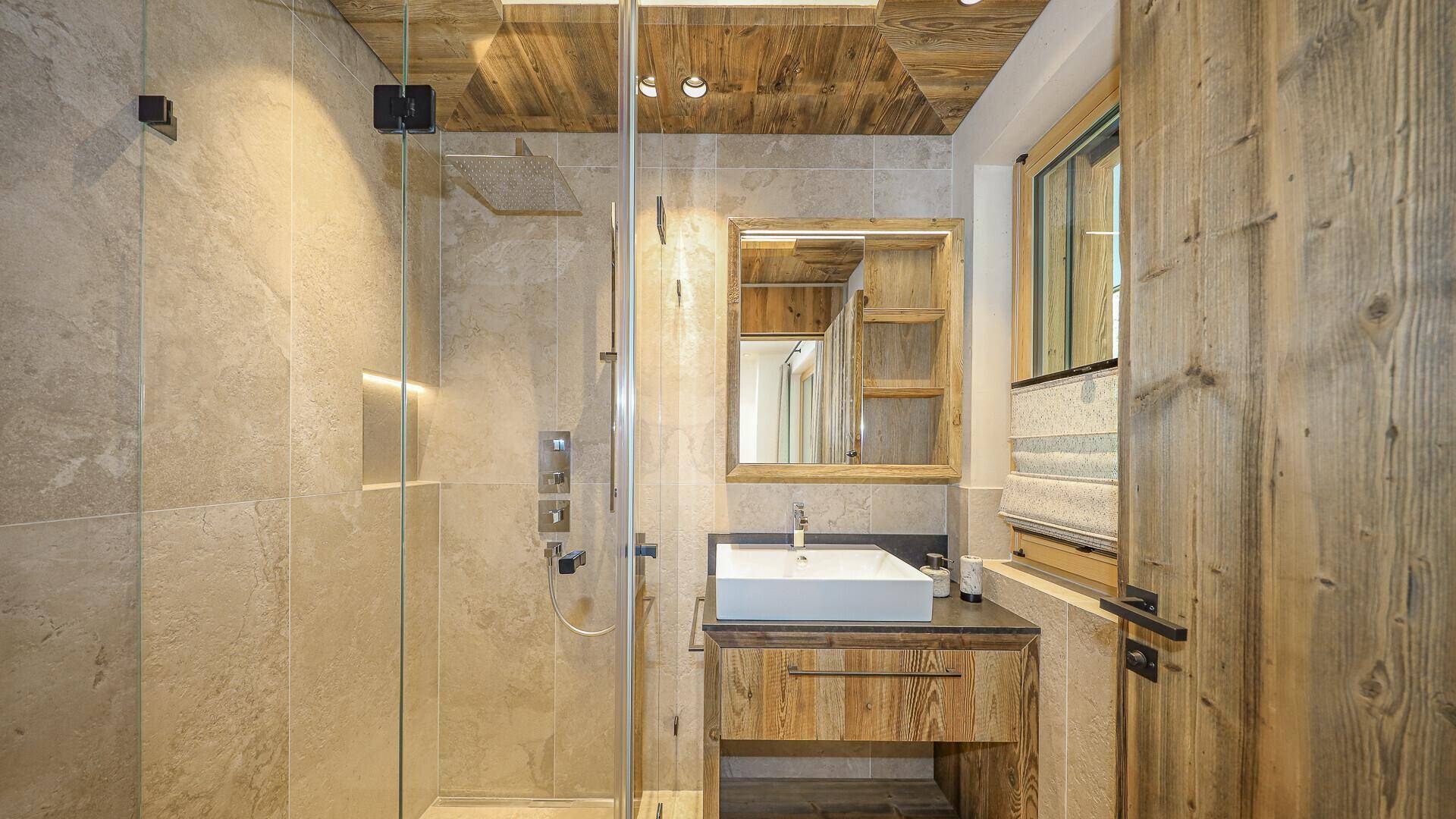 Modernes Badezimmer mit Einzelwaschbecken, begehbarer Dusche und Holzdetails.