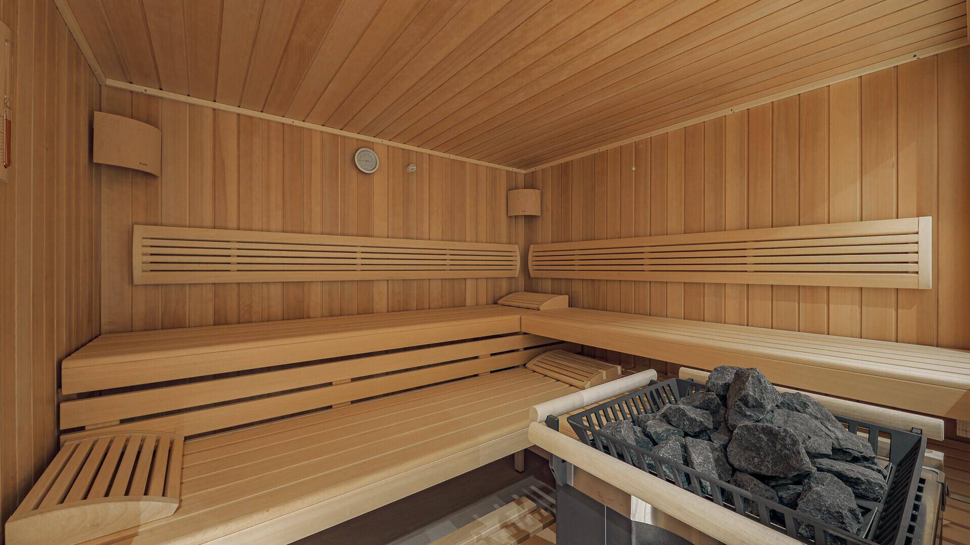 Innenansicht einer traditionellen Holzsauna mit mehreren Bänken und Saunaofen.