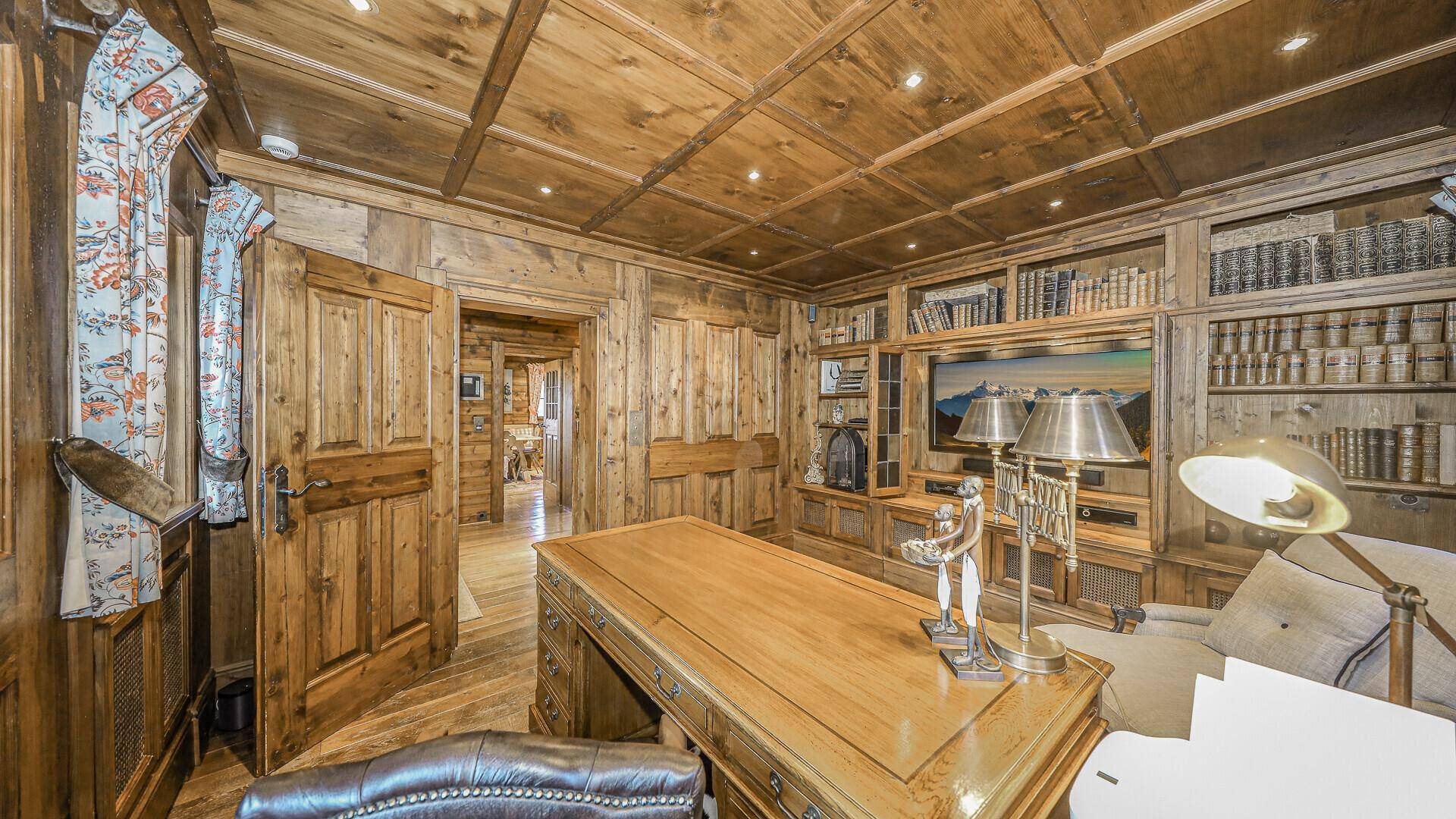 Elegantes Arbeitszimmer mit Holztäfelung, Einbauregalen und großem Schreibtisch.