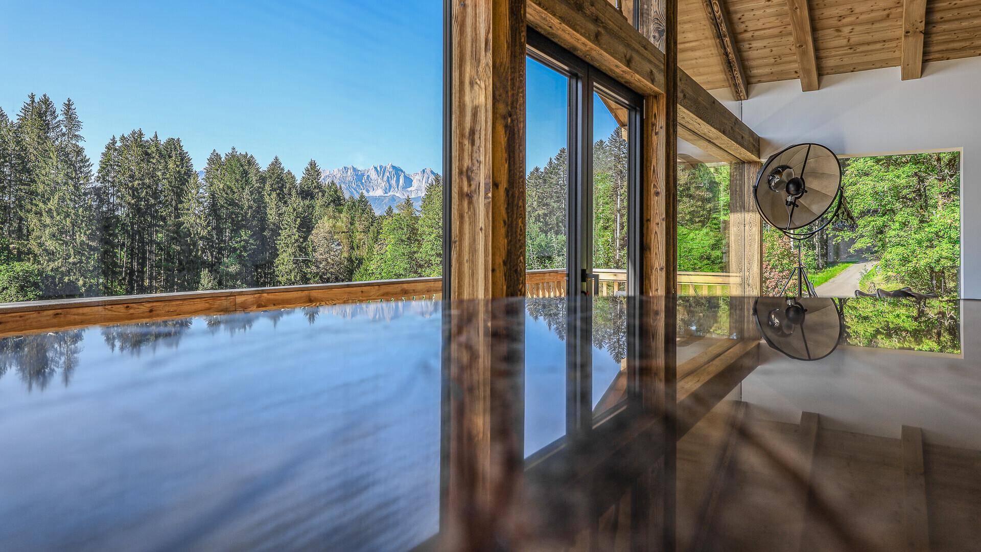 Heller Wohnbereich mit glänzender Oberfläche, großen Fenstern und Blick auf die Berglandschaft.