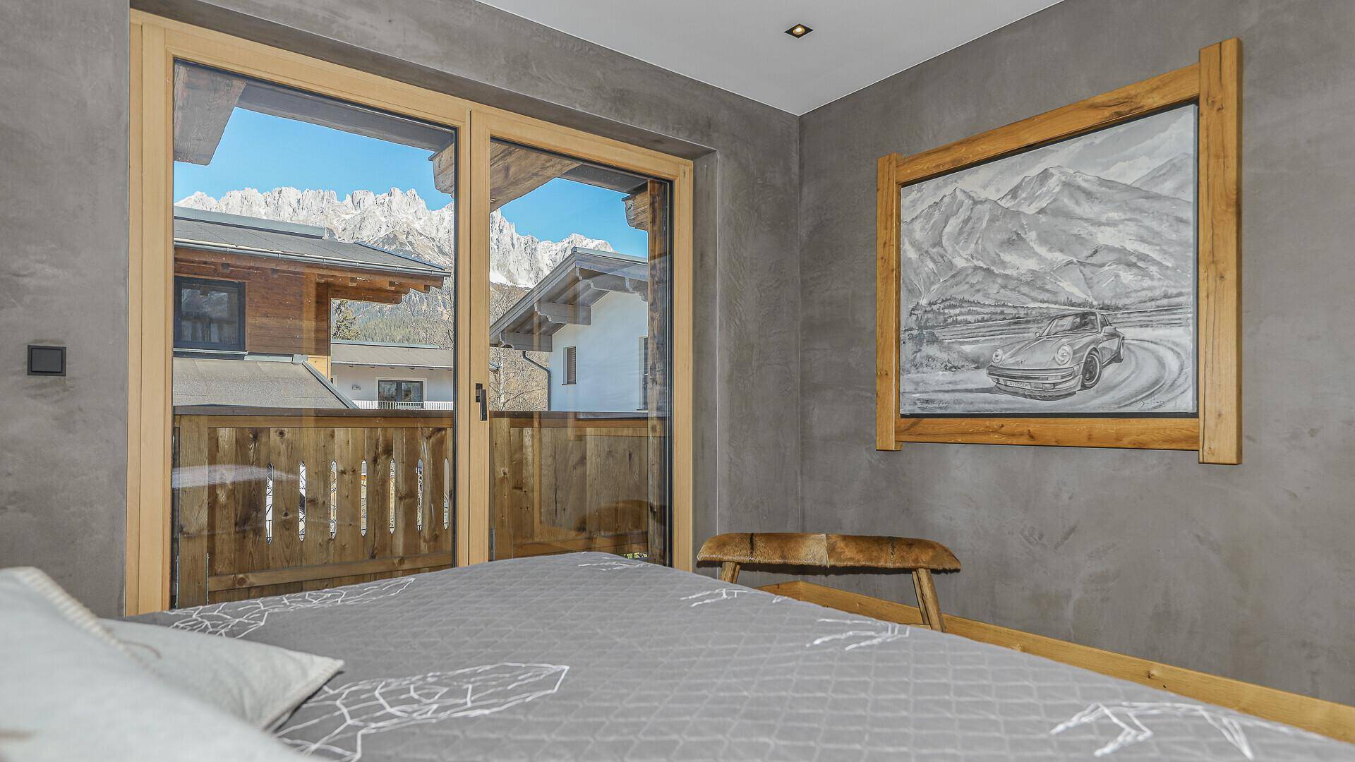 Schlafzimmer mit Balkonzugang und beeindruckendem Bergblick durch große Fenster.