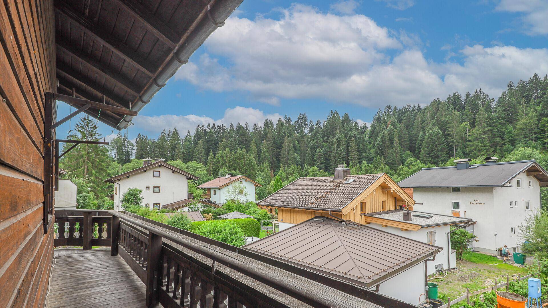 Geräumiger Holzbalkon mit Blick auf die umliegenden Häuser und Wälder.