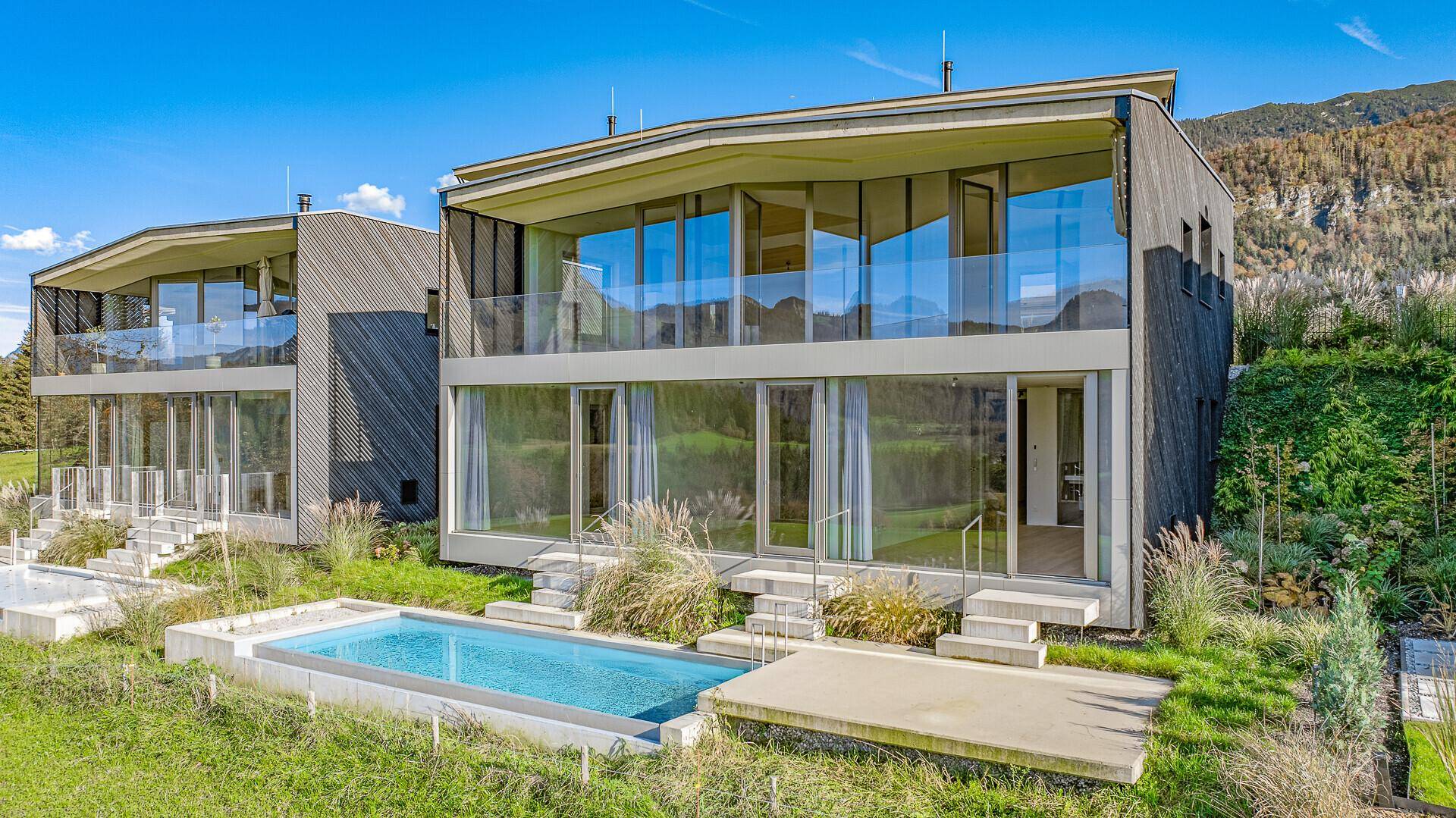 Moderne Architektur mit großen Glasfronten, Balkonen und einem kleinen Pool im Vordergrund.
