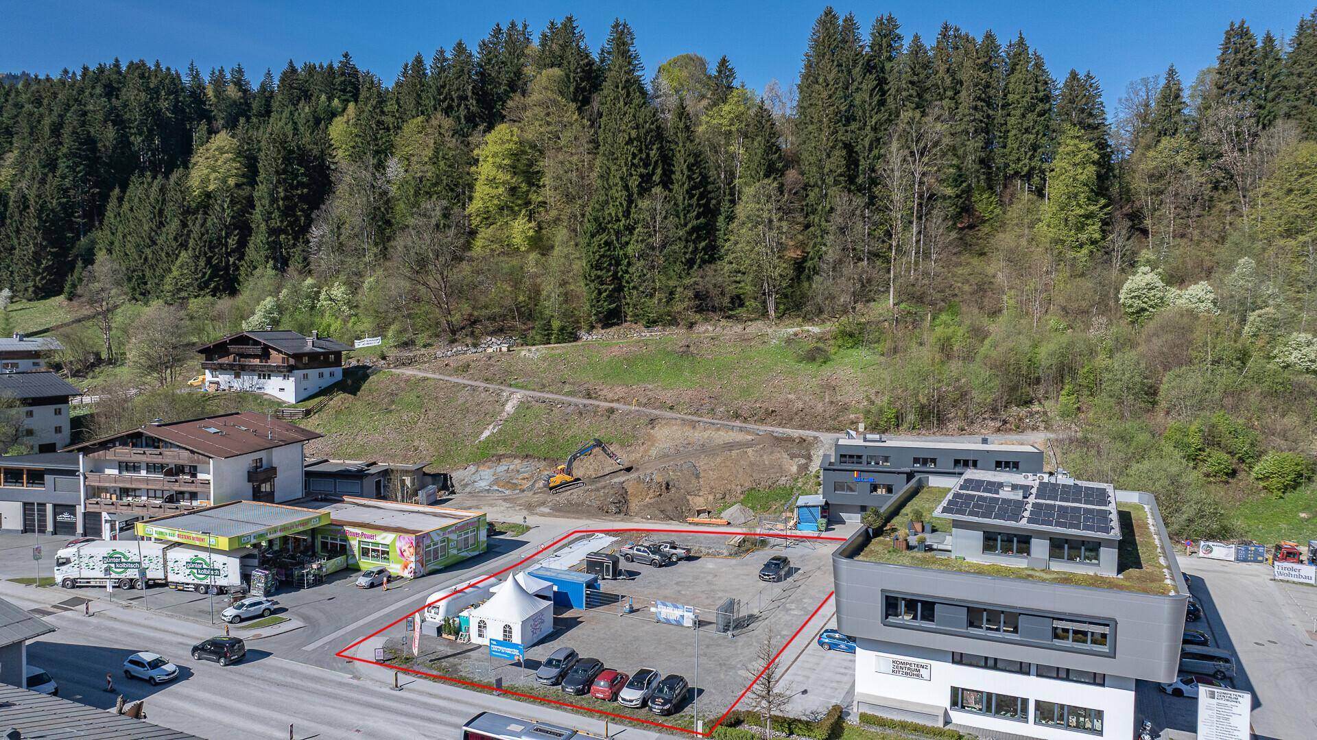 Nahaufnahme des Grundstücks von oben mit angrenzenden Geschäften und einer Baustelle im Hintergrund.