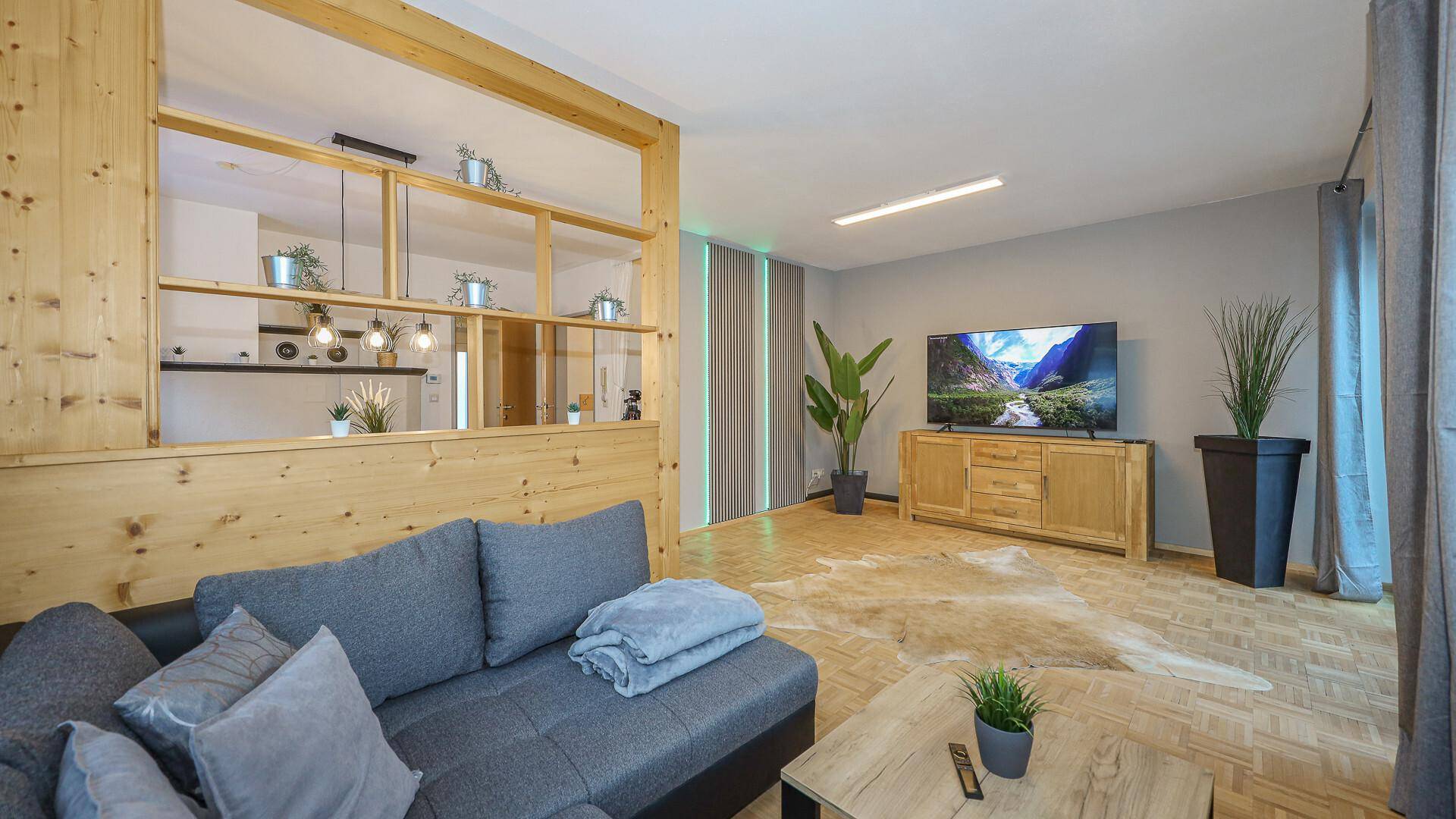 Heller Wohnbereich mit bequemer Couch, Holzelementen und Blick auf den Essbereich.
