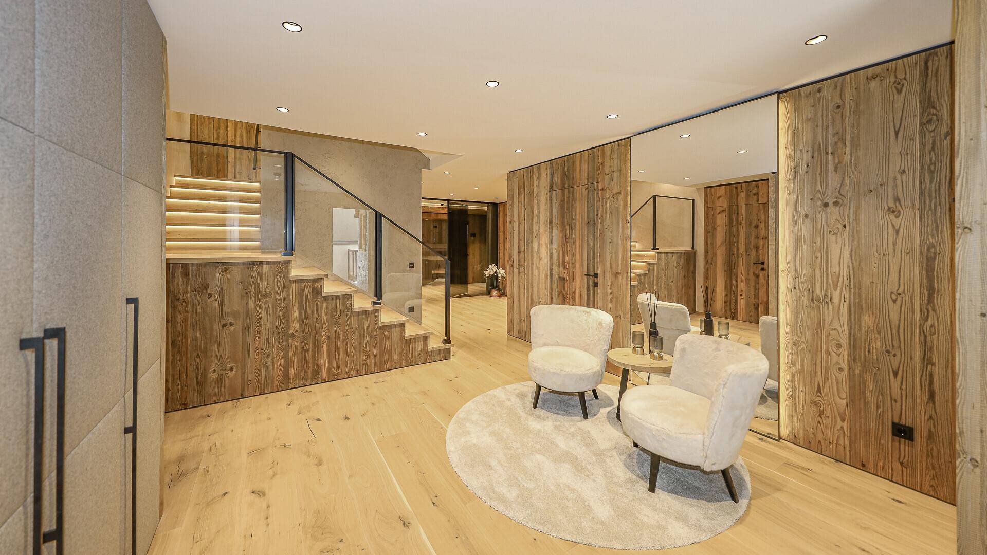 Stilvoller Flur mit Holztreppe, Glasgeländer und gemütlicher Sitzecke.