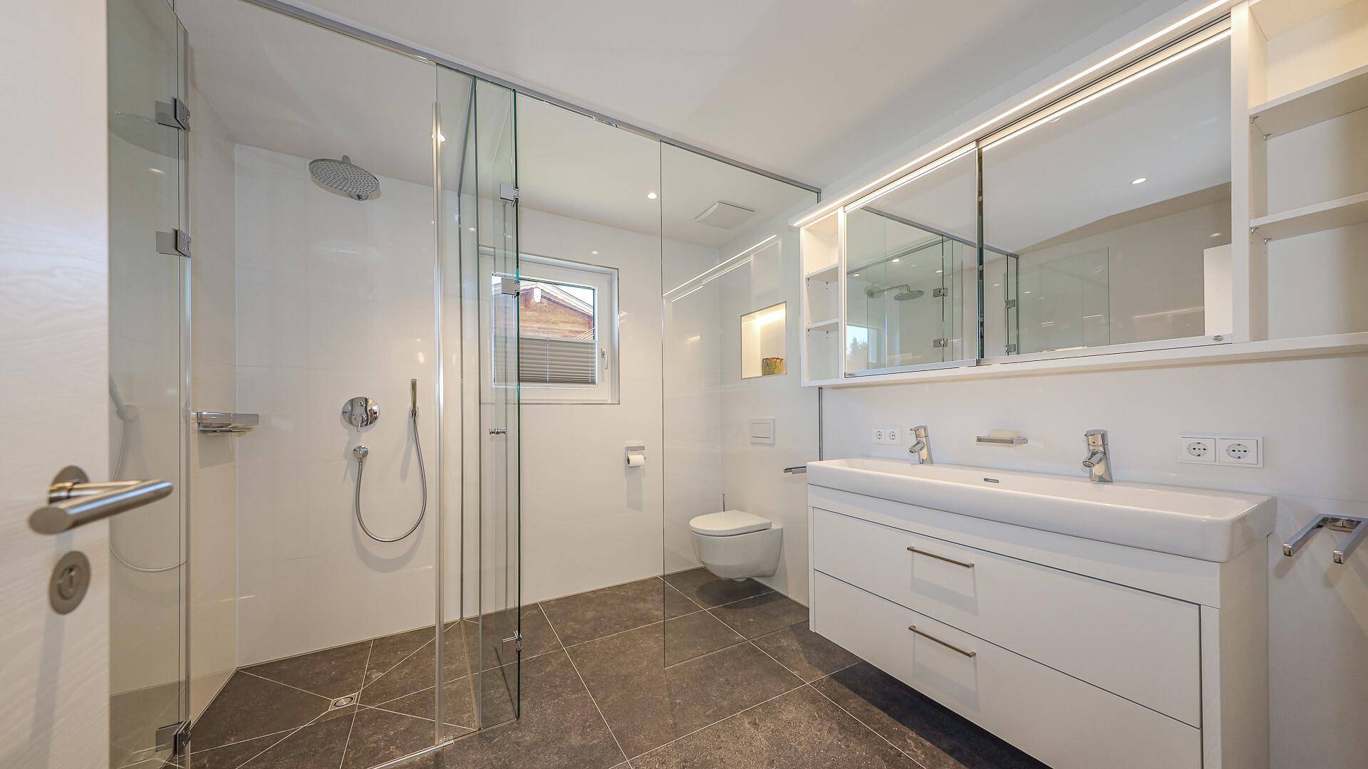 Modernes Badezimmer mit großer begehbarer Dusche, Doppelwaschbecken und Fenster.
