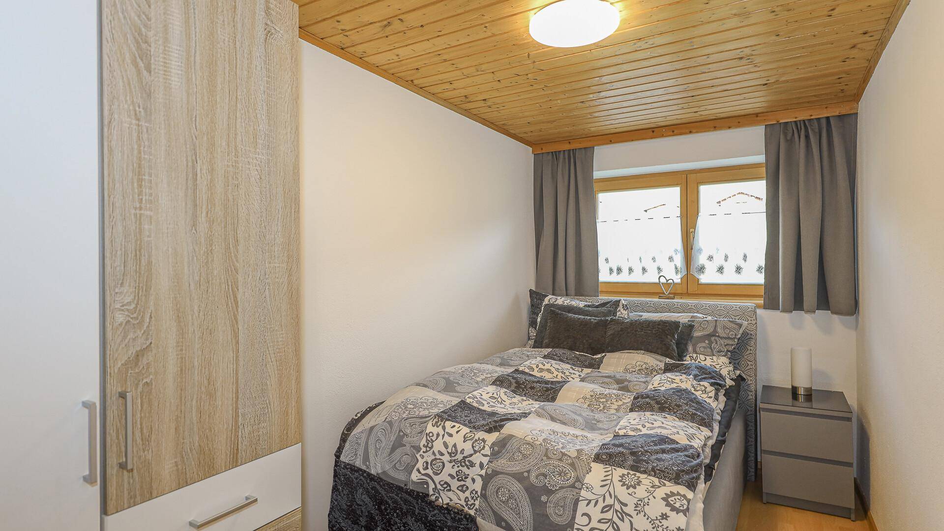 Gemütliches Schlafzimmer mit Einzelbett, Holzdecke und Kleiderschrank.