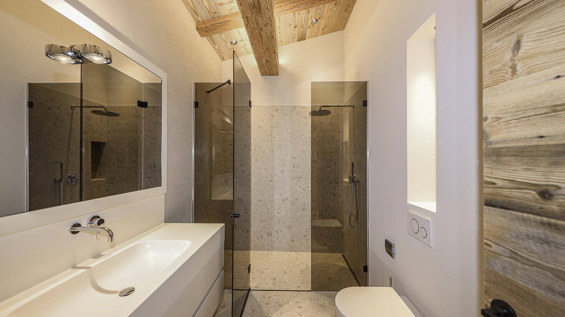 Modernes Badezimmer mit Doppel-Walk-in-Dusche, Einzelwaschbecken und Wand-WC.