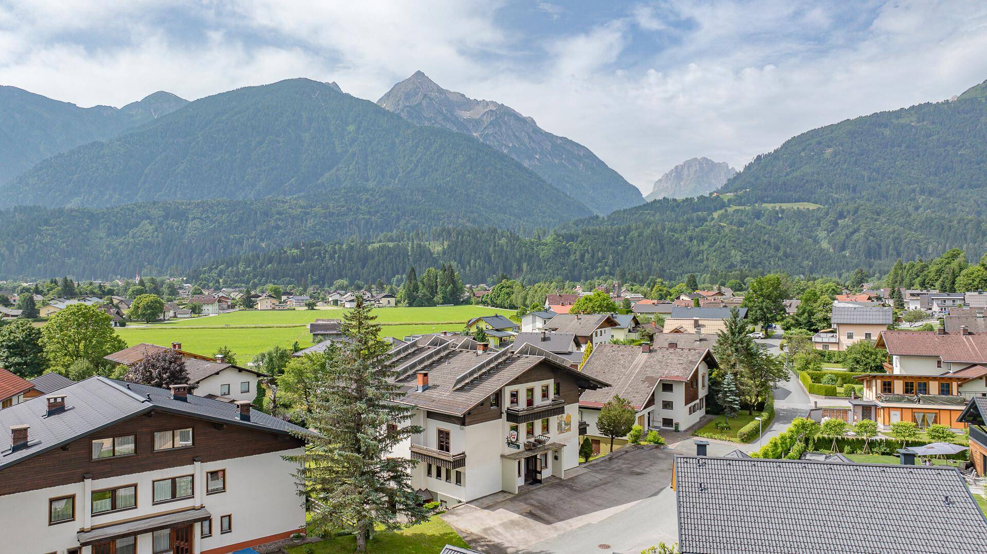 Panoramablick über ein charmantes Dorf mit traditionellen Häusern und einer beeindruckenden Bergkulisse.