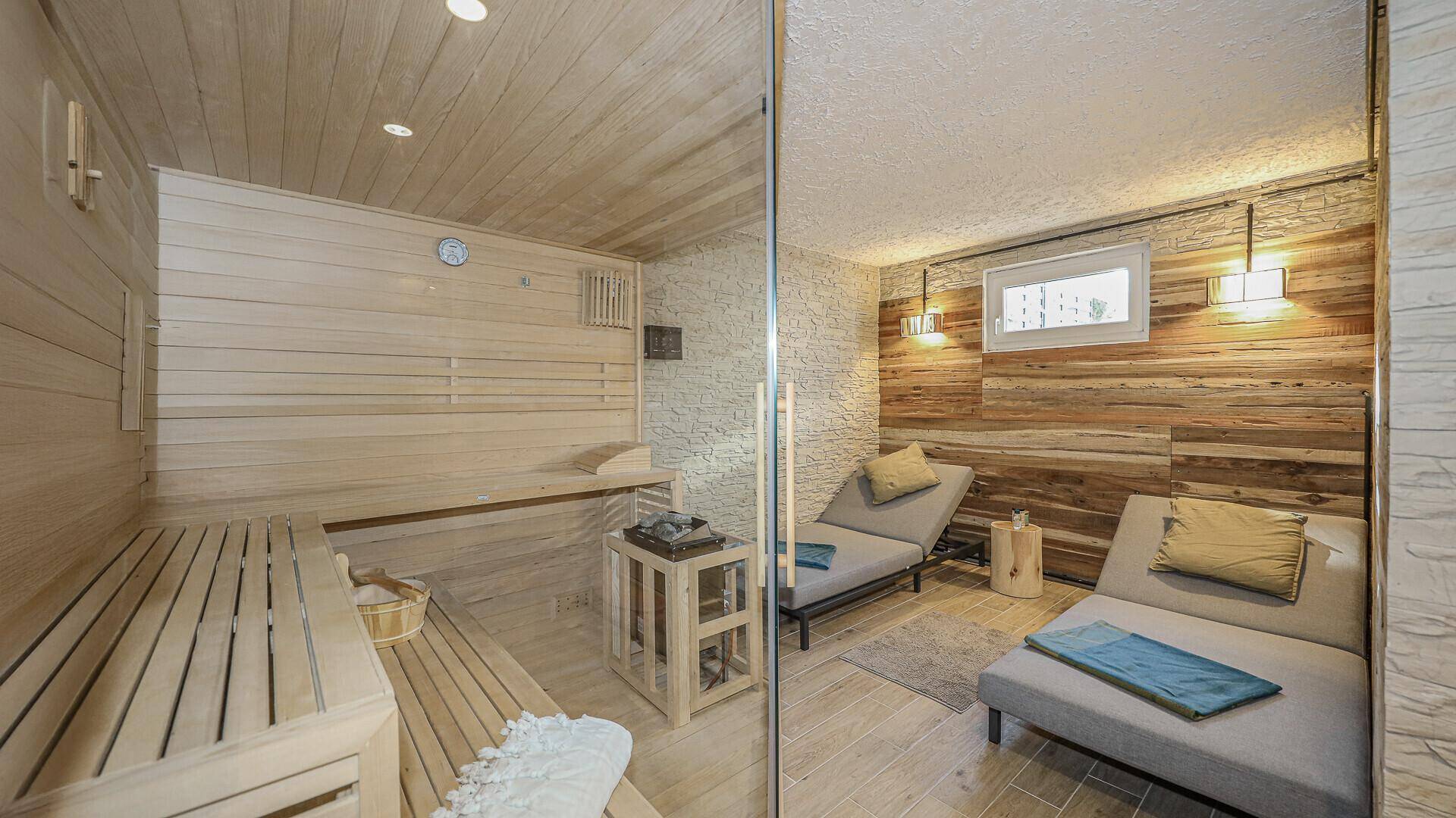Entspannender Wellnessbereich mit holzverkleideter Sauna und bequemen Liegen zum Ausruhen.