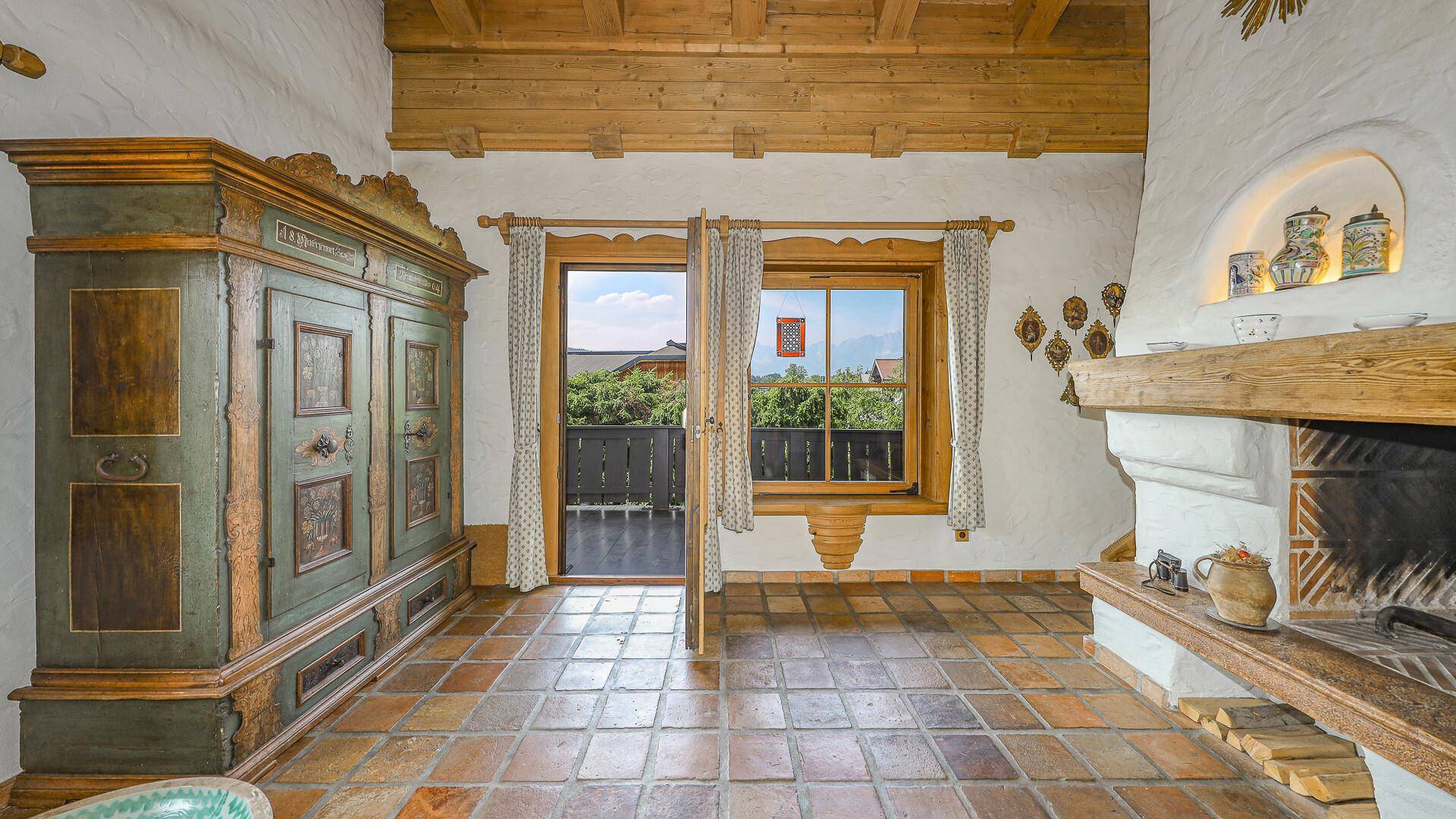 Wohnzimmer mit Kamin, rustikalem Schrank und Zugang zu einem Balkon mit Bergblick.