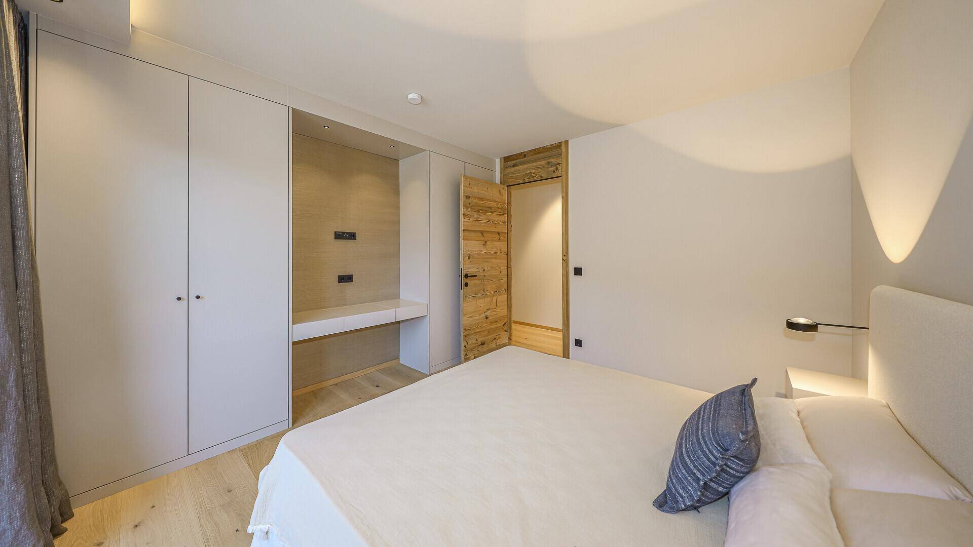 Helles Schlafzimmer mit integrierten Kleiderschränken und Holzboden.