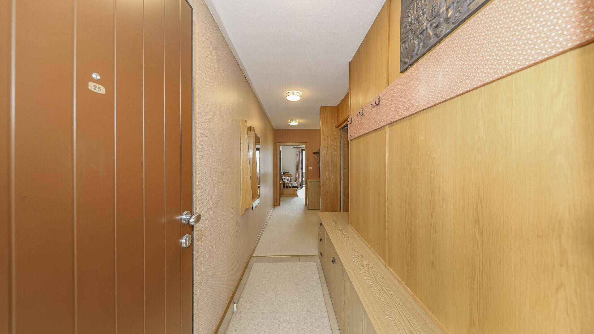 Eingangsbereich mit Holztür, Garderobe und Teppichboden, im traditionellen Stil gehalten.