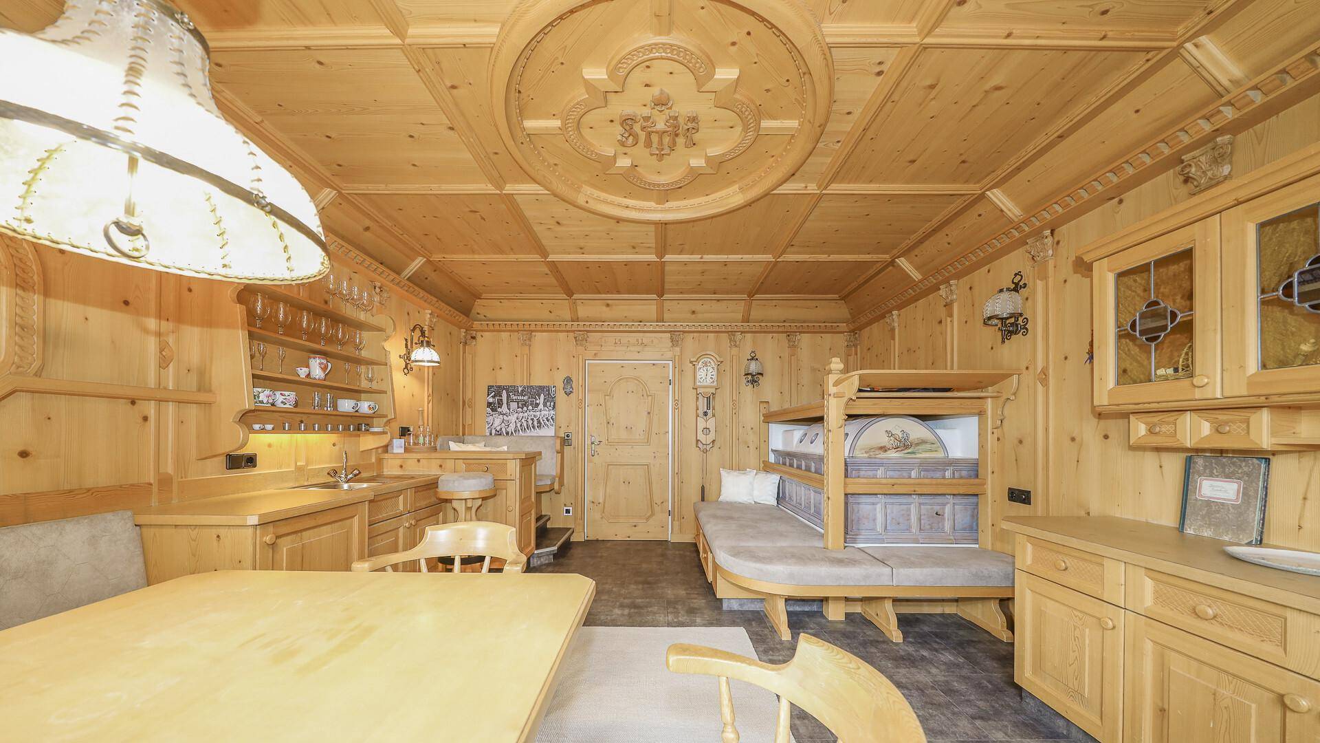 Gemütlicher Wohn- und Essbereich mit integrierter Küchenzeile und einem charmanten Etagenbett, alles in Holz gehalten.