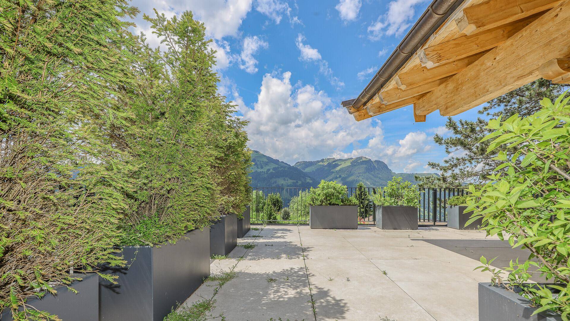 Große Terrasse mit Pflanzenkübeln und weitem Blick auf die umliegende Berglandschaft.