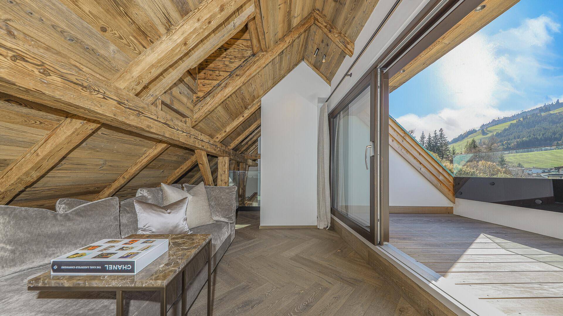 Gemütlicher Wohnbereich mit Zugang zu einer Dachterrasse und Bergblick.