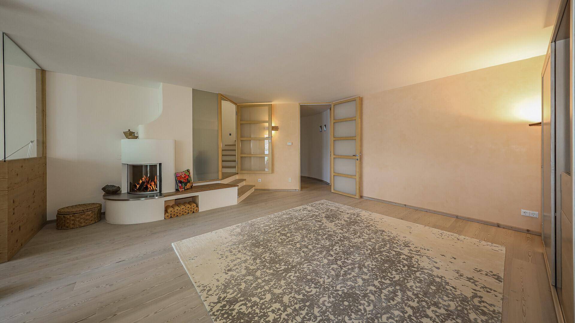 Gemütliches Wohnzimmer mit Holzboden, Kamin und integrierter Holzablage, ideal für entspannte Abende.