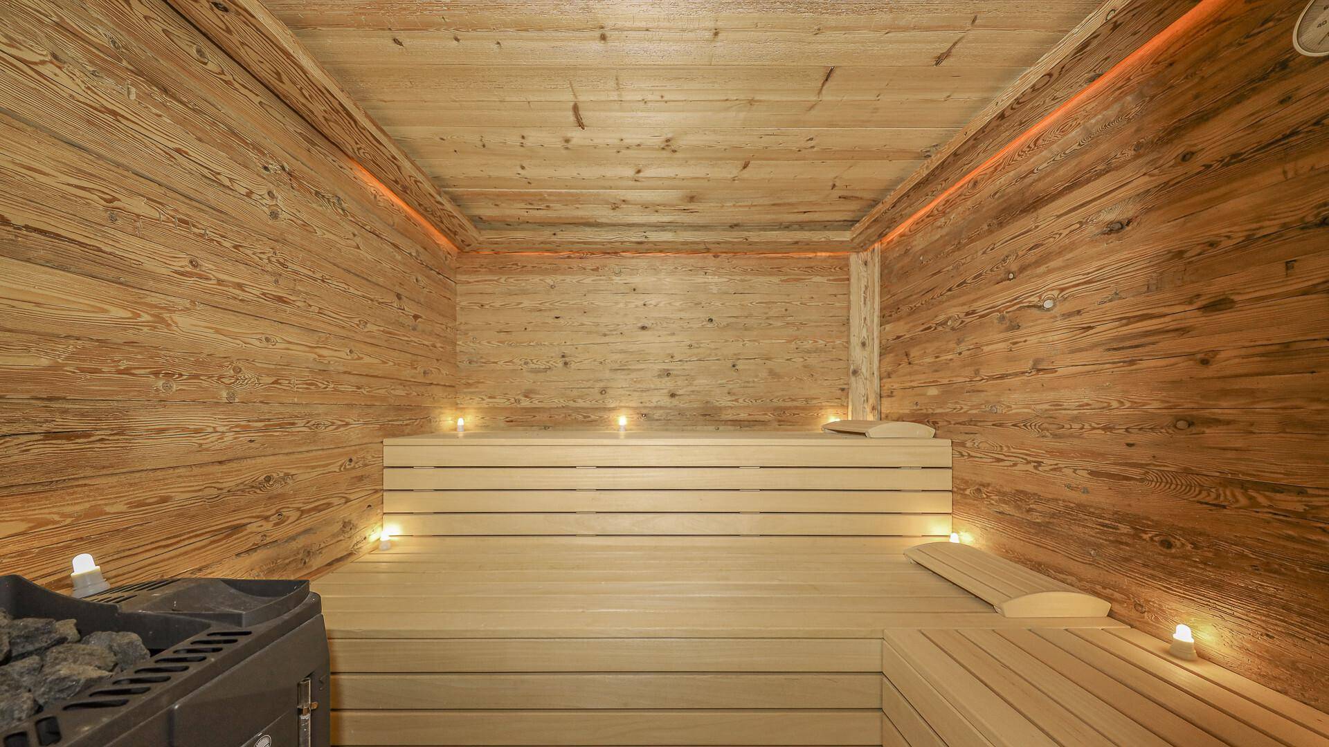 Geräumige Holzsauna mit stimmungsvoller Beleuchtung und bequemen Bänken für Entspannung.