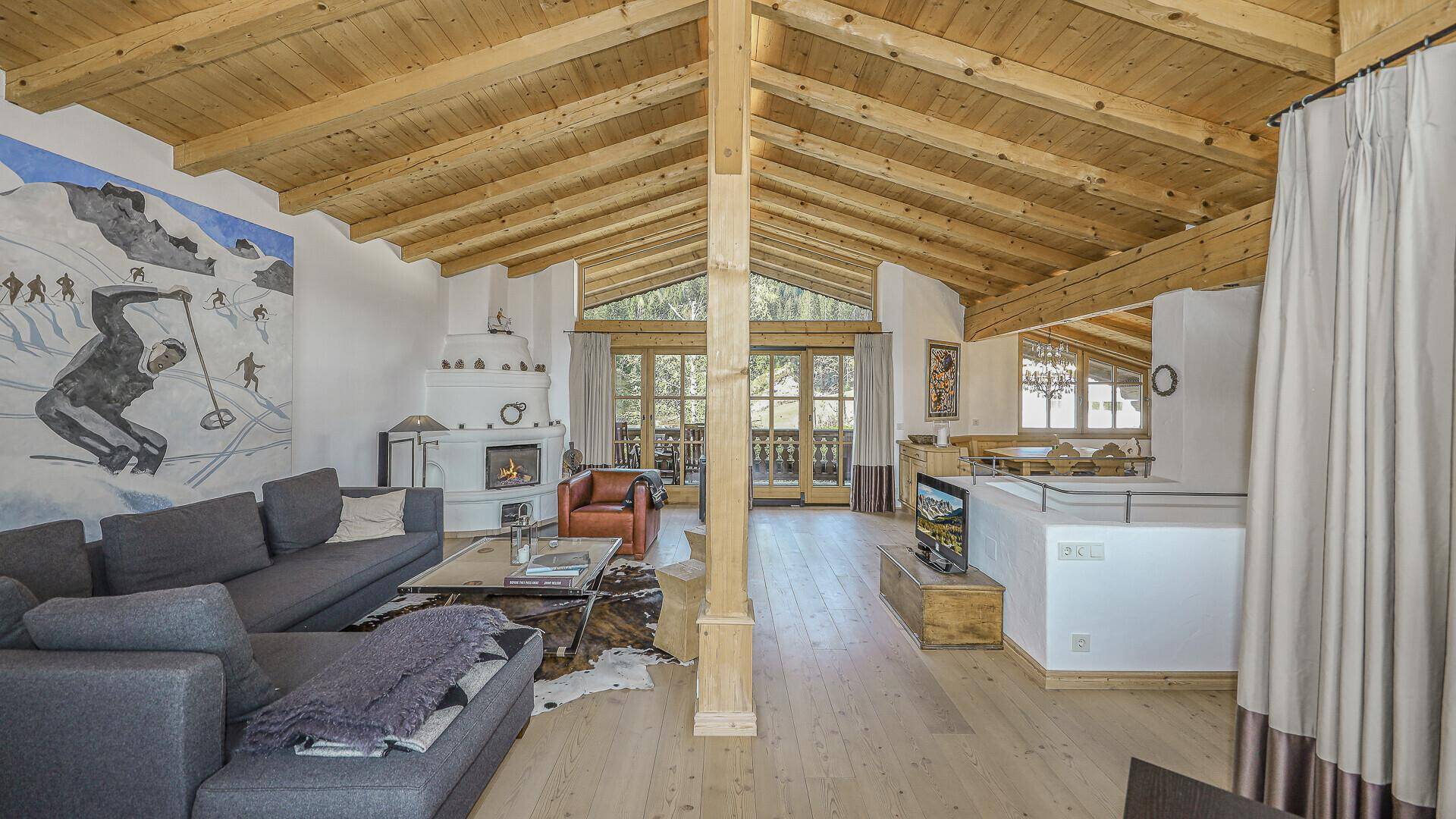 Offener Wohn- und Essbereich mit Holzbalkendecke, Kamin und Zugang zum Balkon.
