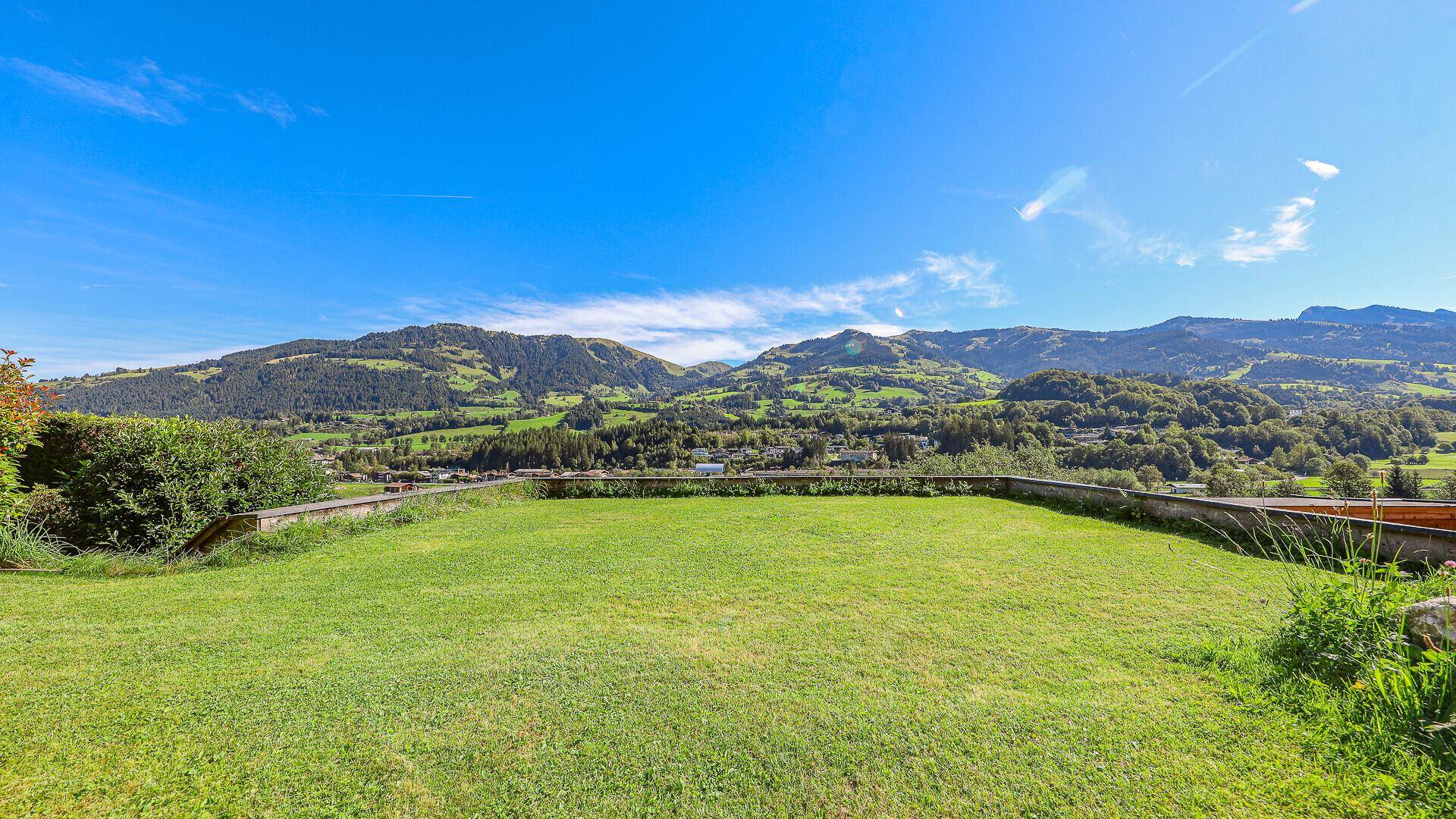 Weitläufiger Gartenbereich mit gepflegtem Rasen und Panoramablick auf die sanften Hügel und Berge.