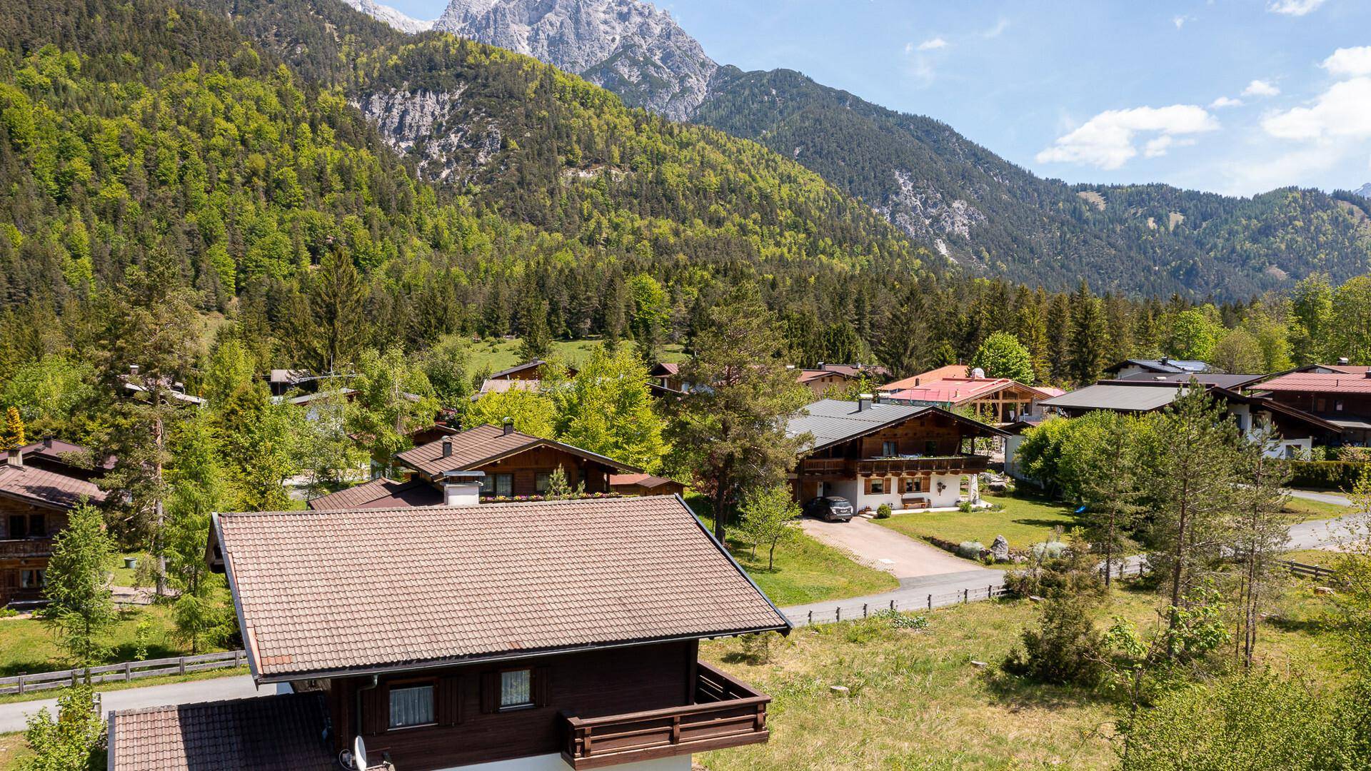 Panoramablick auf ein alpines Dorf mit traditionellen Häusern und majestätischen Bergen im Hintergrund.