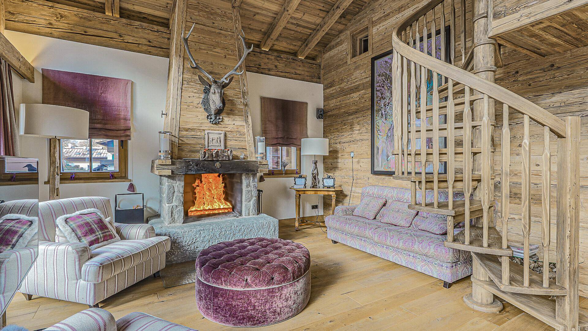 Gemütliches Wohnzimmer mit Kamin, Geweih-Dekoration und rustikalem Holzinterieur.