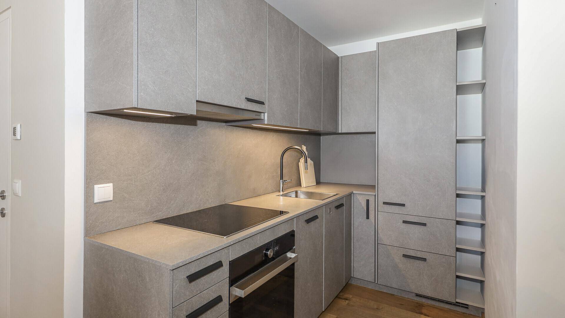 Moderne Einbauküche in Grau mit Induktionskochfeld, Backofen und ausreichend Stauraum.
