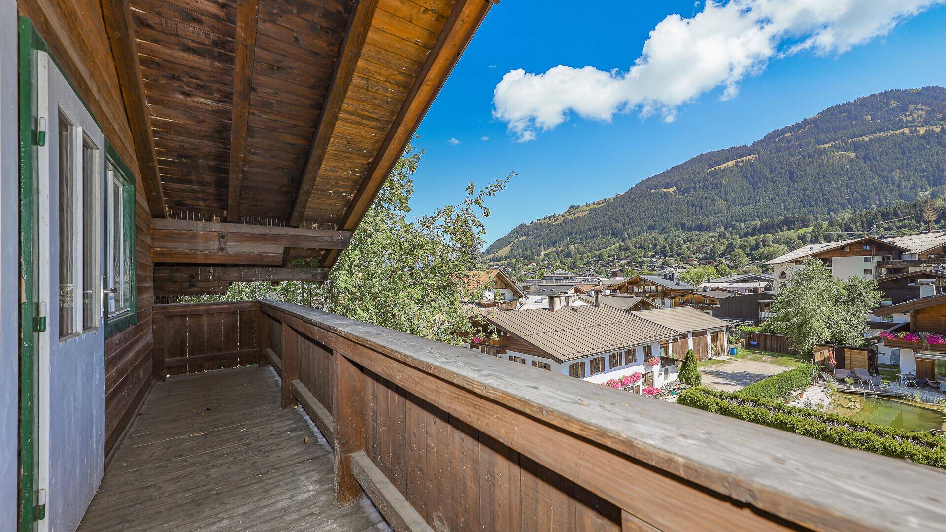 Geräumiger Holzbalkon mit Blick auf die grünen Berge und die umliegende Bebauung.