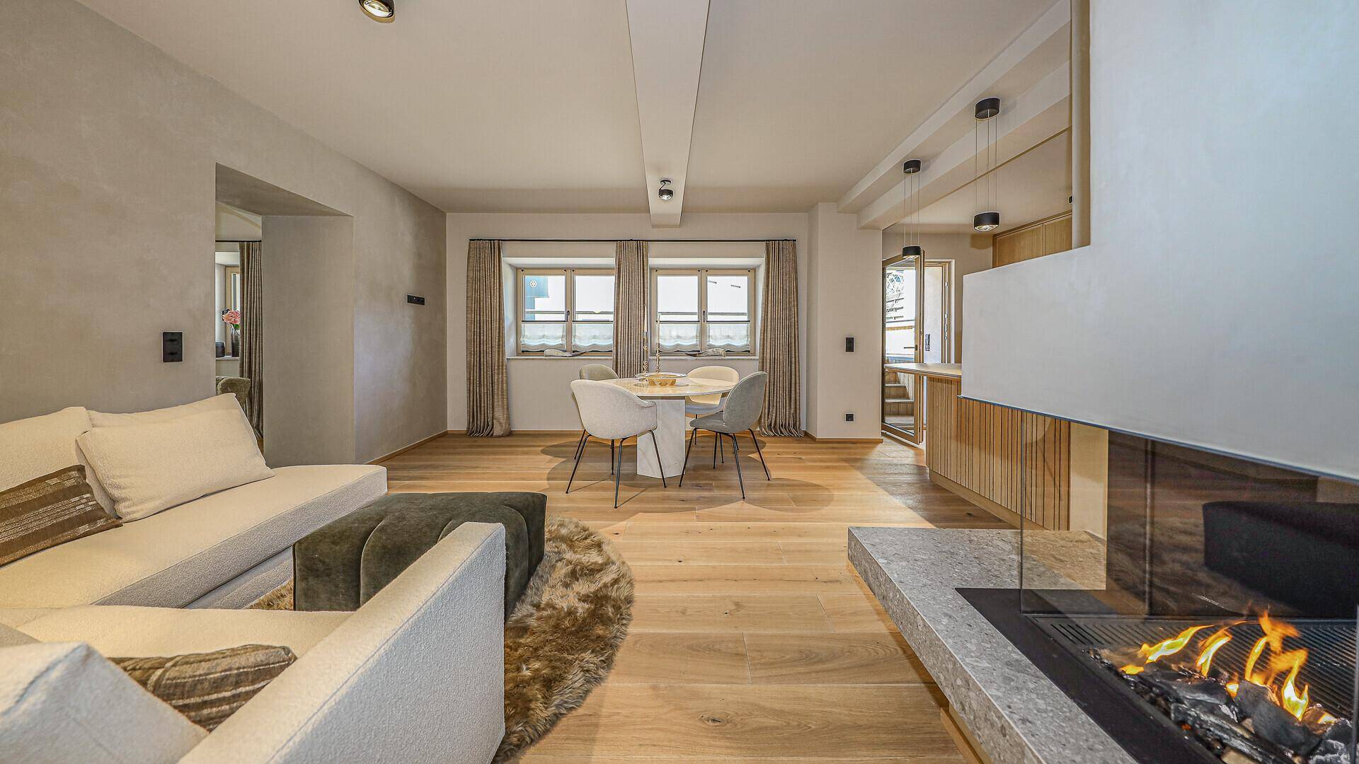 Geräumiger Wohn-Essbereich mit Kamin, Holzboden und Zugang zur modernen Küche.