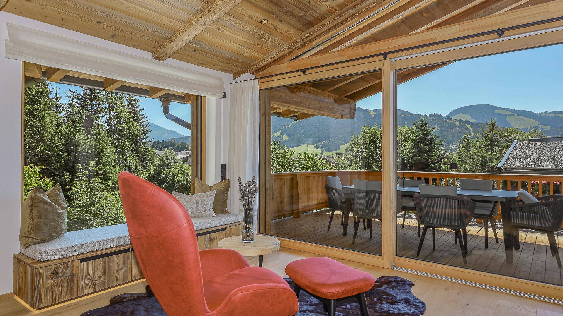 Gemütliche Leseecke mit Bergblick, großen Schiebetüren und Zugang zum möblierten Balkon.
